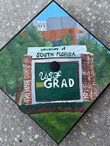 Painted USF grad cap of the Tampa campus front entrance sign with text reading "University of South Florida, USF Grad"