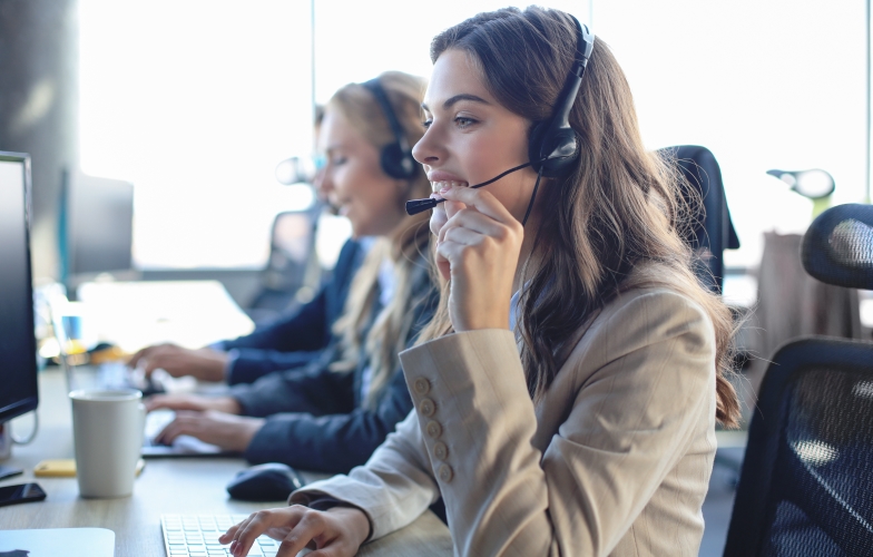 A woman on a headset conversing at a computer