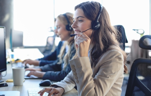 A woman on a headset conversing at a computer