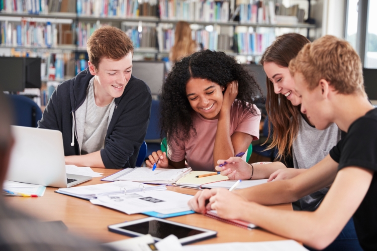 A group of high school students studying together in the library