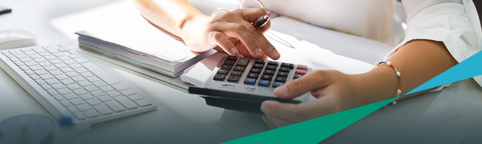 A woman holding a pen and a calculator by her desk for financial resources