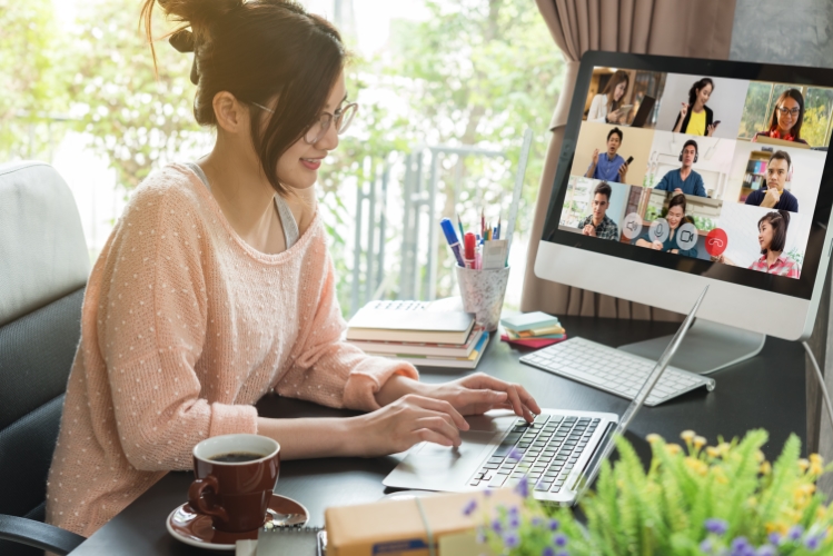 A woman working at a laptop while on a video conference with a team