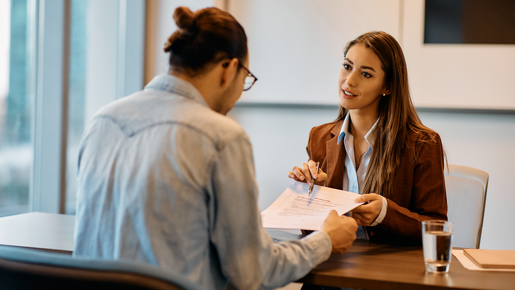 woman points to paper while discussing with a man