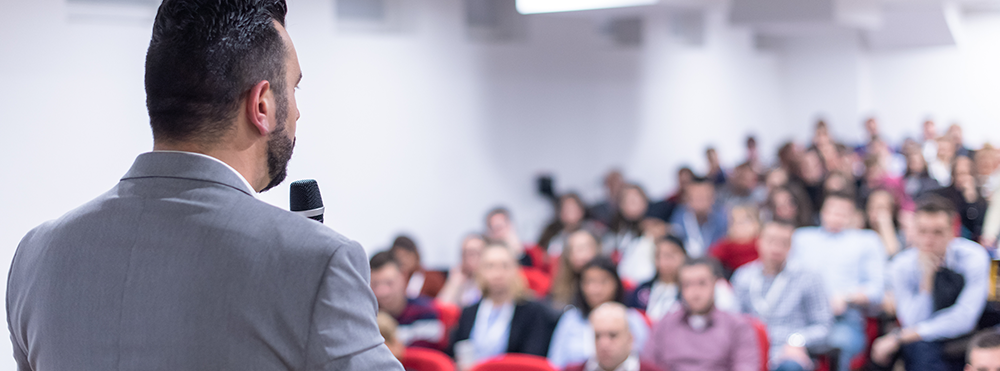 man stands at front of class speaking