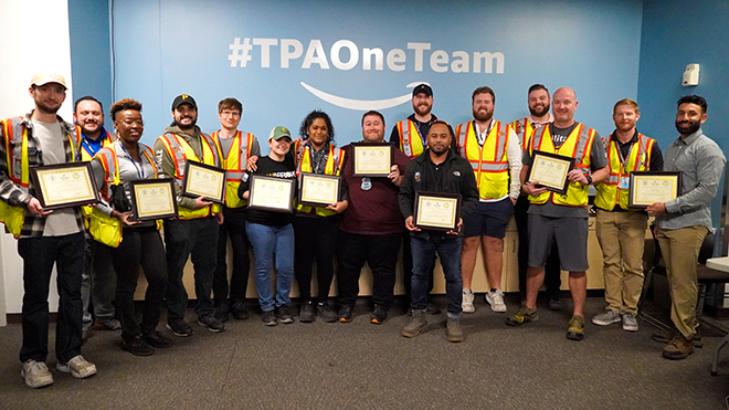 a group of amazon workers pose with certificates after graduating lean six sigma