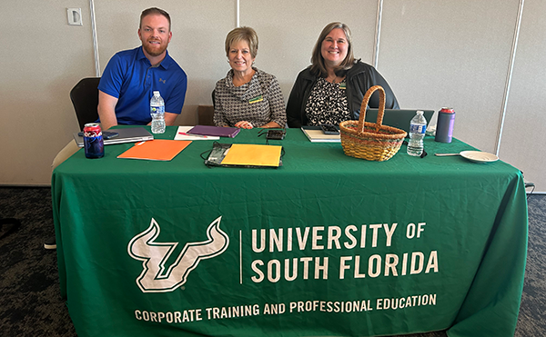 3 members of usf corporate training and development post for picture behind table