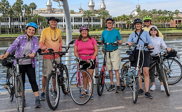 a group of older adults smile and pose while riding their bikes