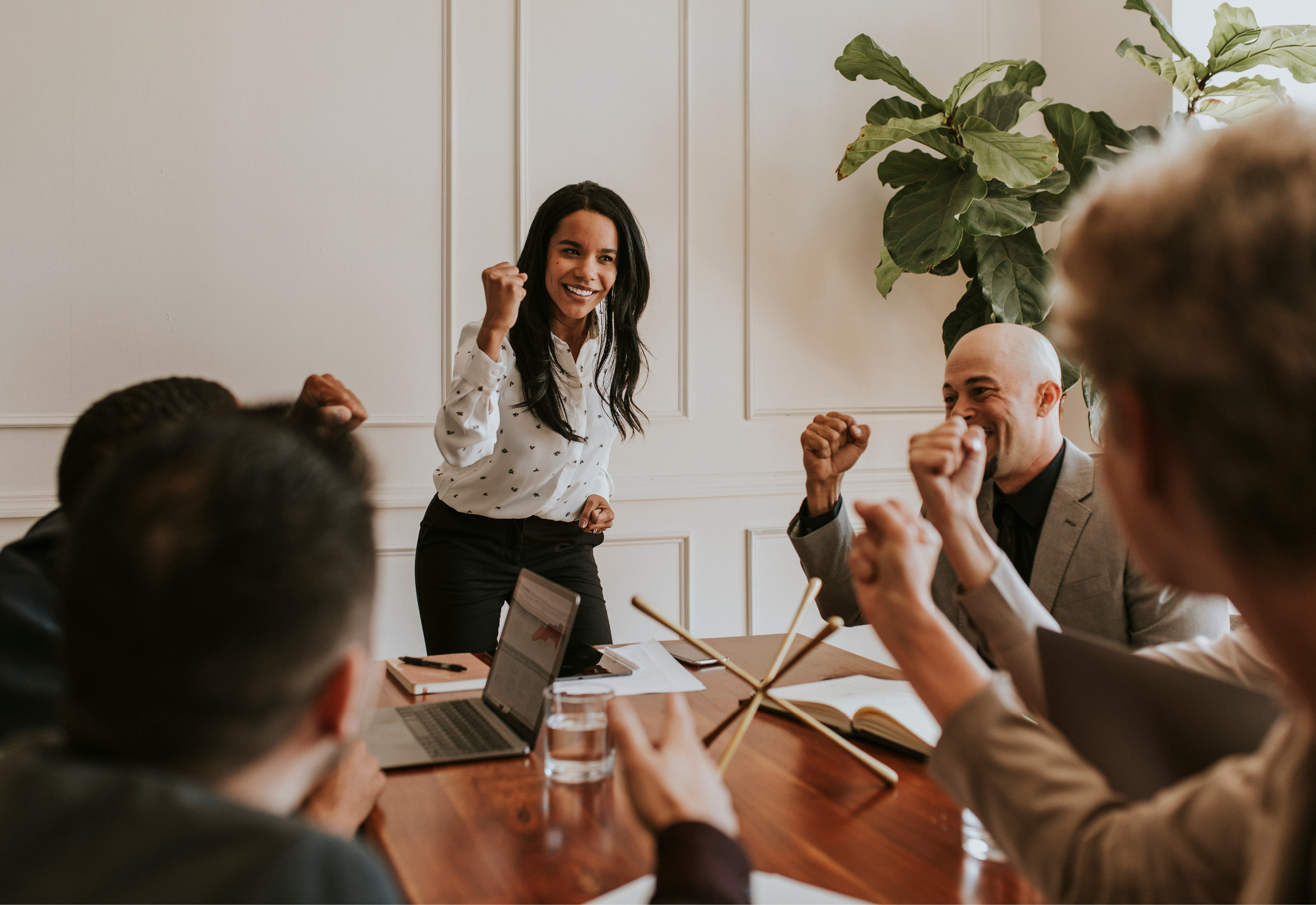 A group of people sitting around a table smiling with their fists raised in the air
