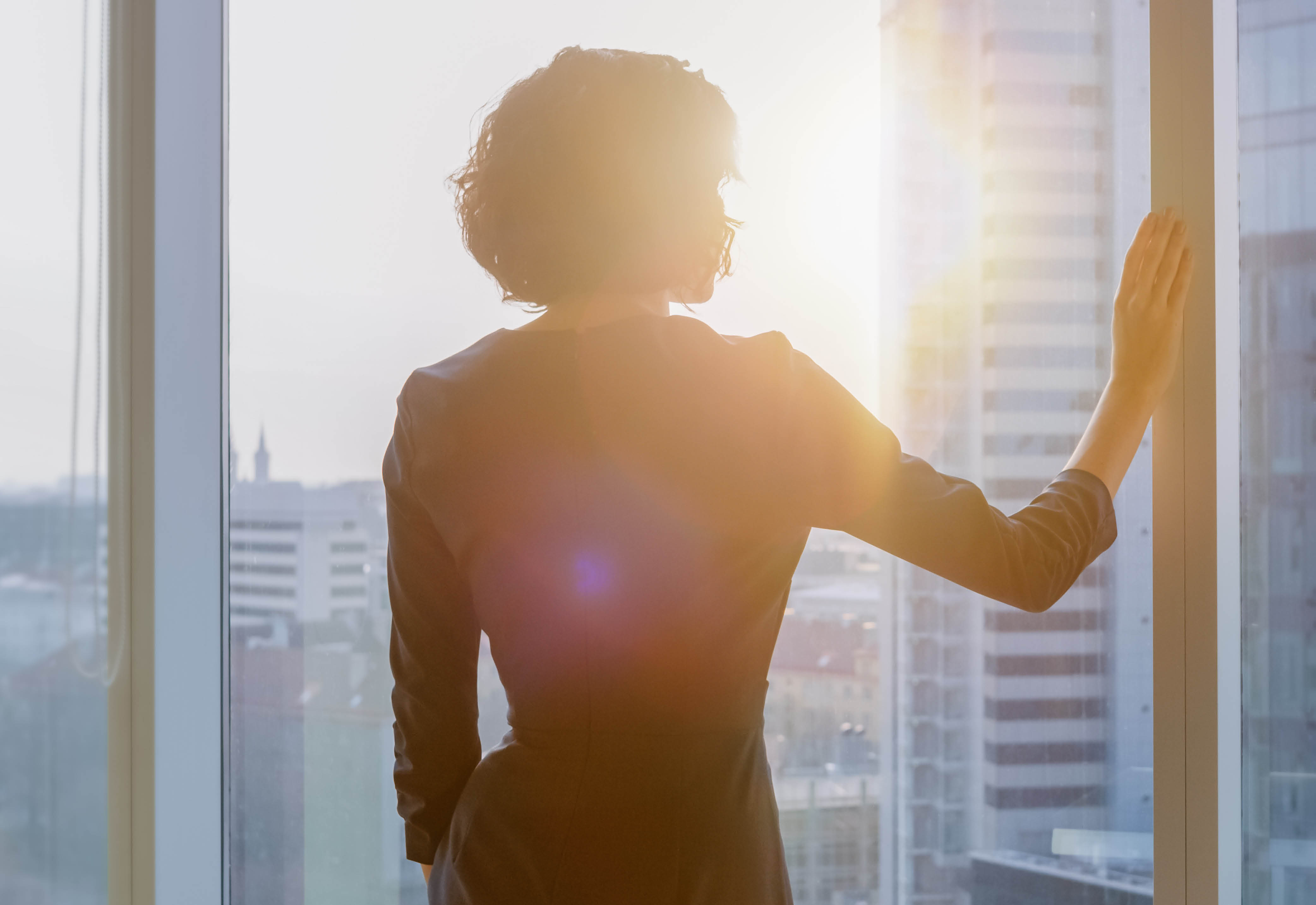 A woman looking out of a window at the city skyline