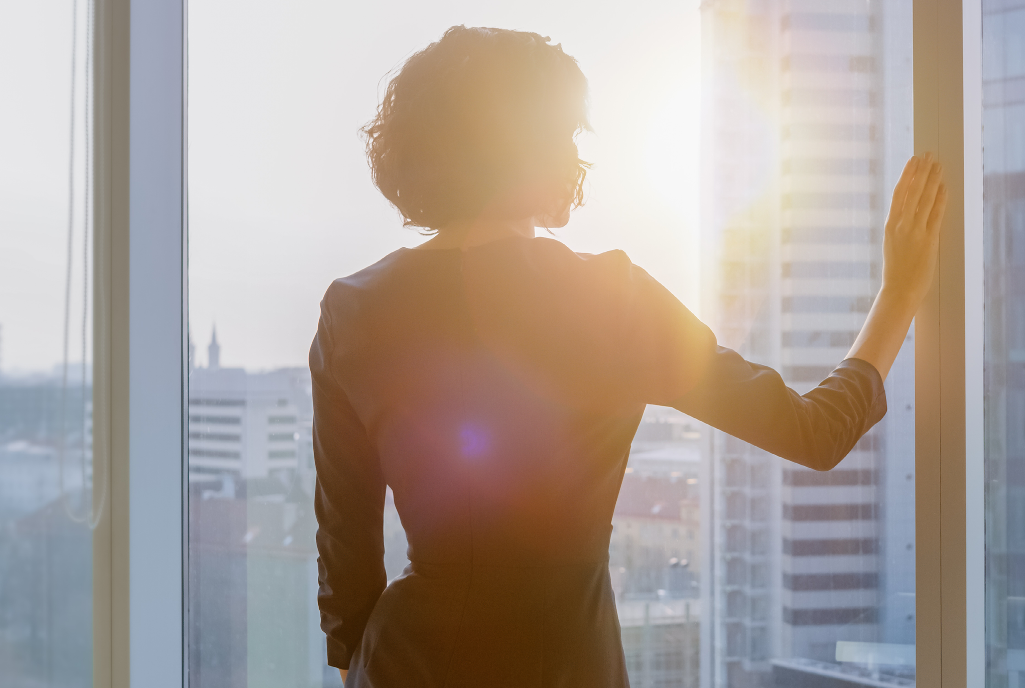 A woman looking out of a window at the city skyline