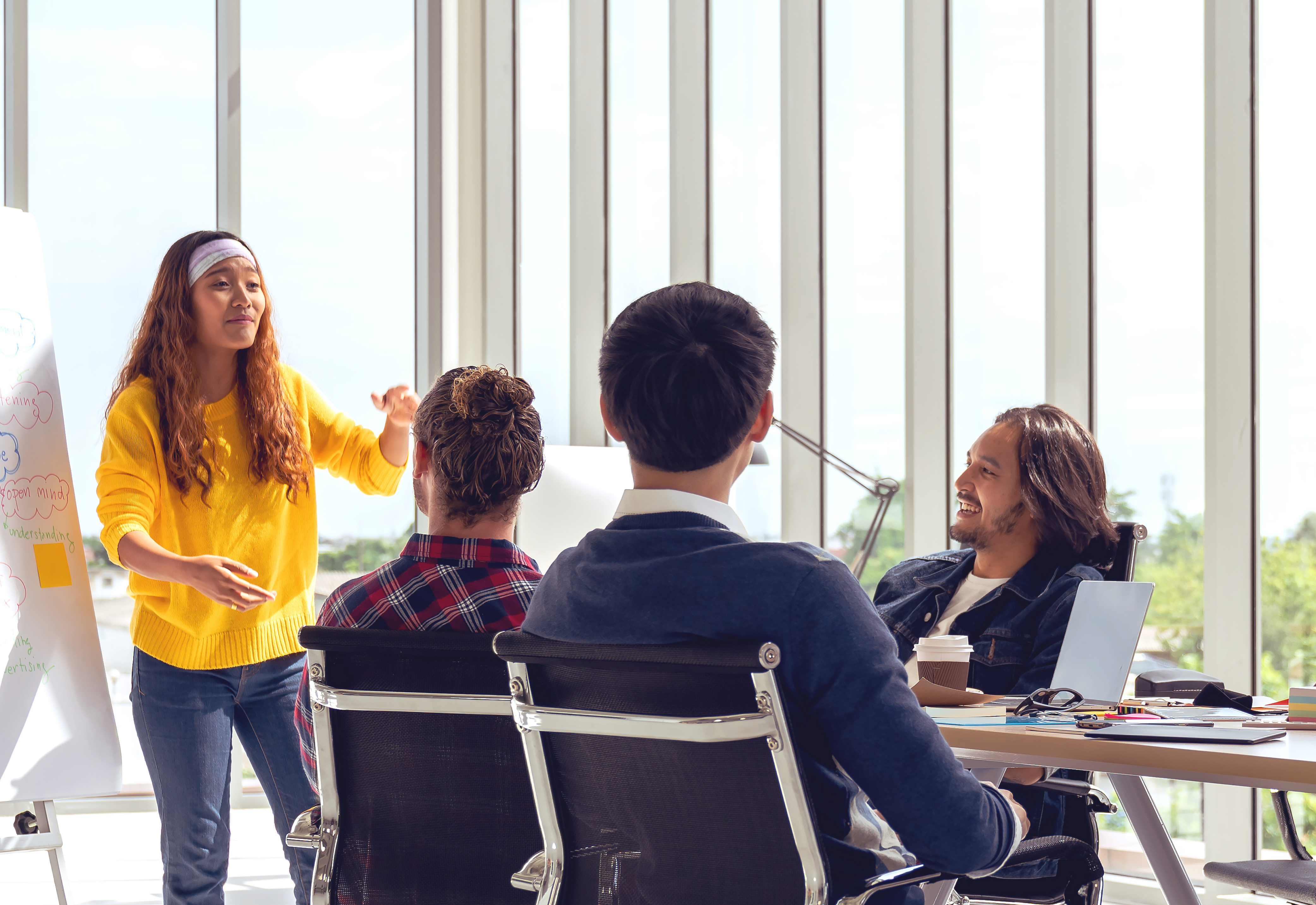 A woman giving a presentation to a group of people sitting at a table
