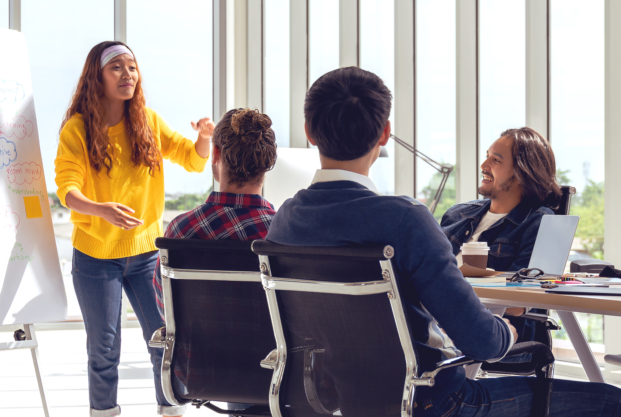 A woman giving a presentation to a group of people sitting at a table