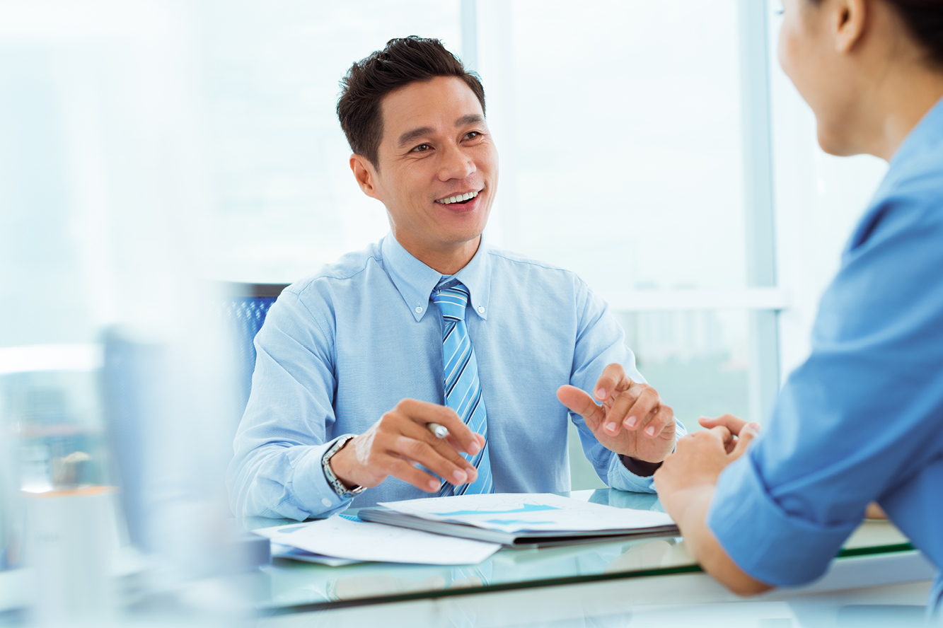 A man and woman sitting at a desk wearing blue button down shirts