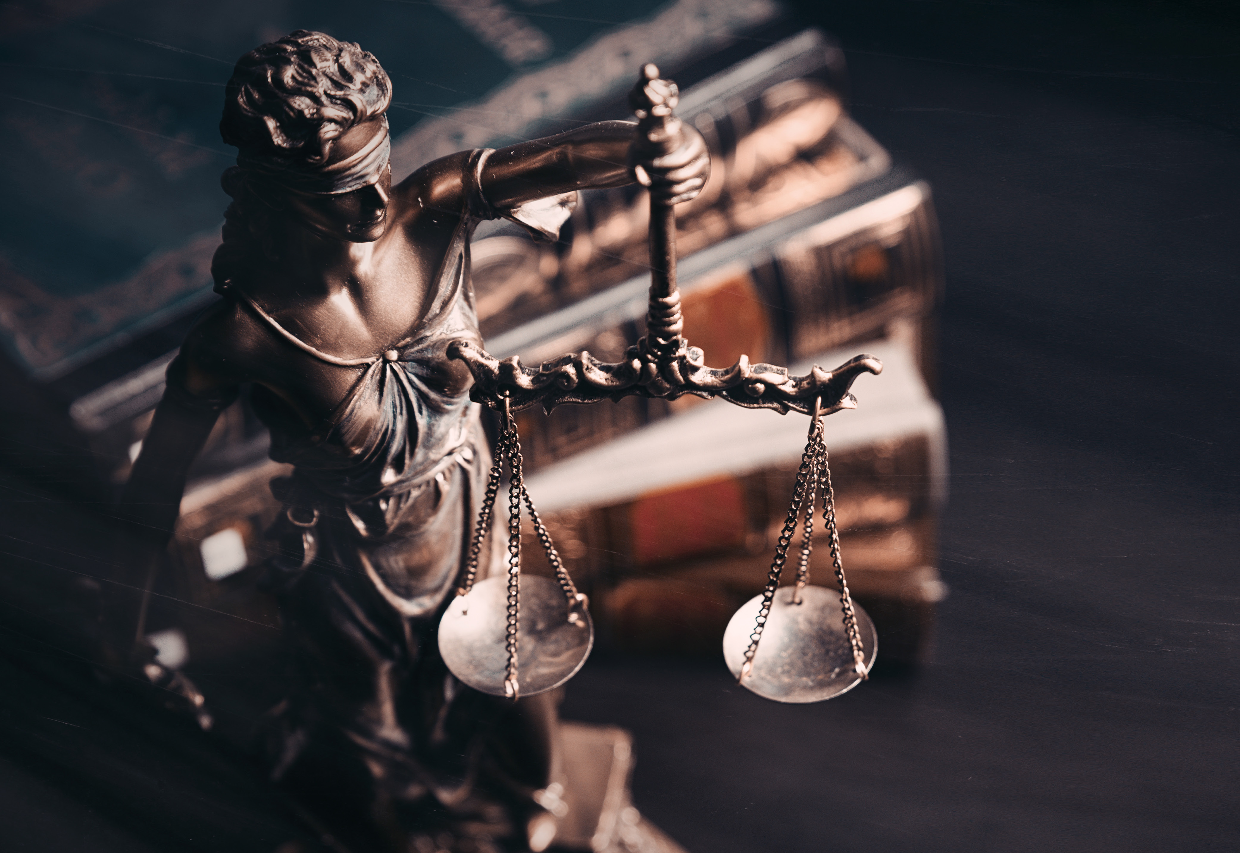A Lady Justice statue next to a stack of books