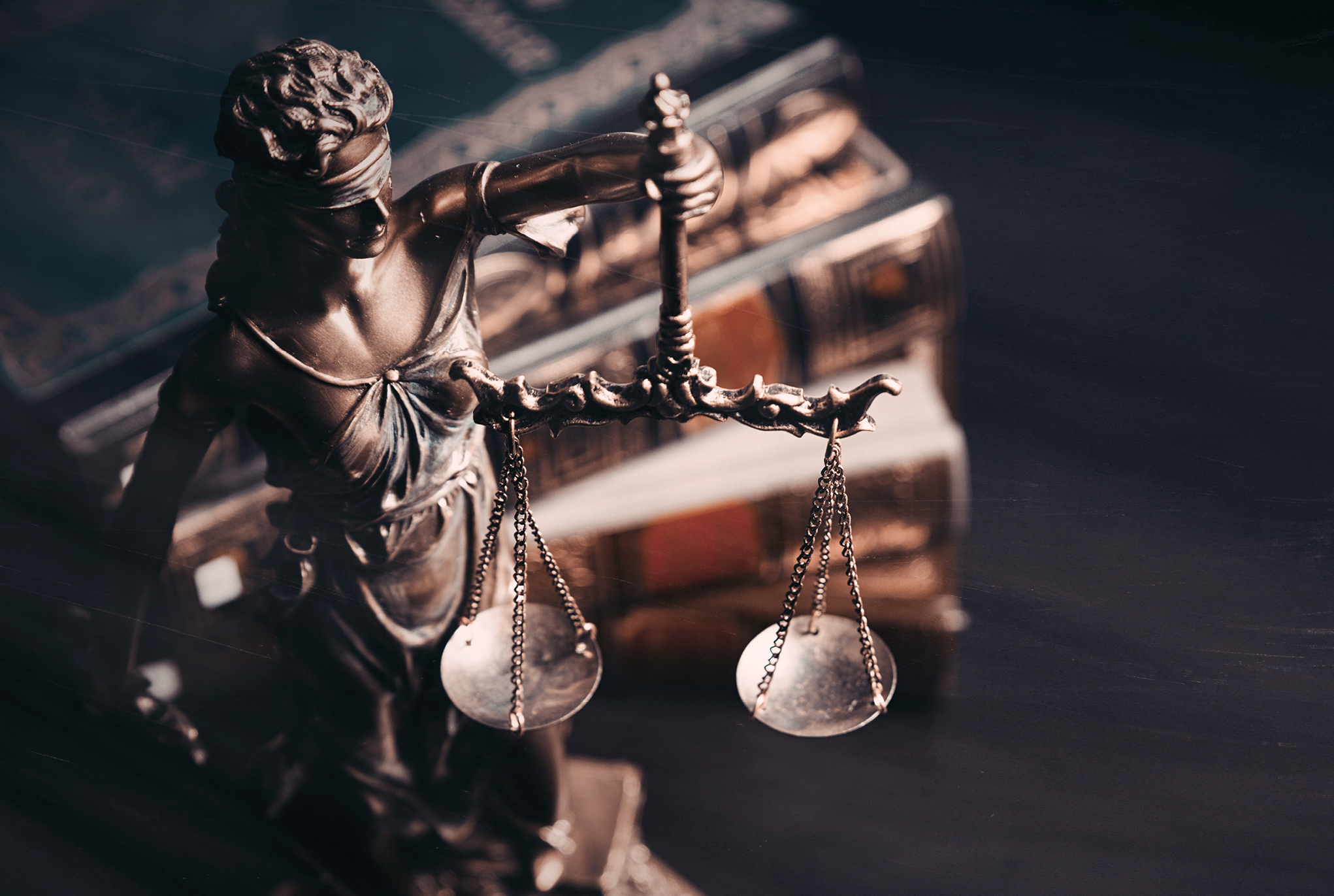 A Lady Justice statue next to a stack of books