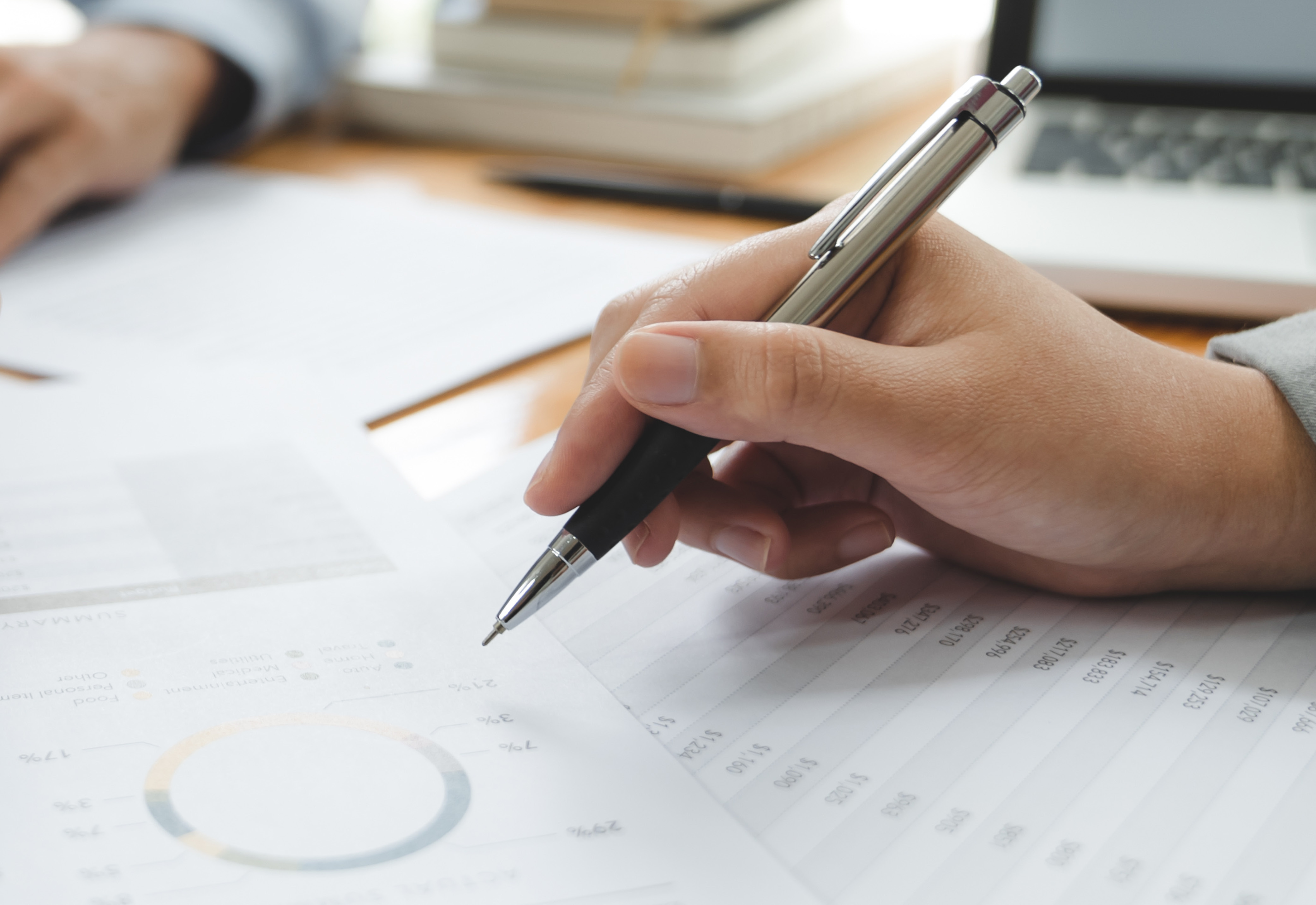 A hand holding a pen on top of paperwork