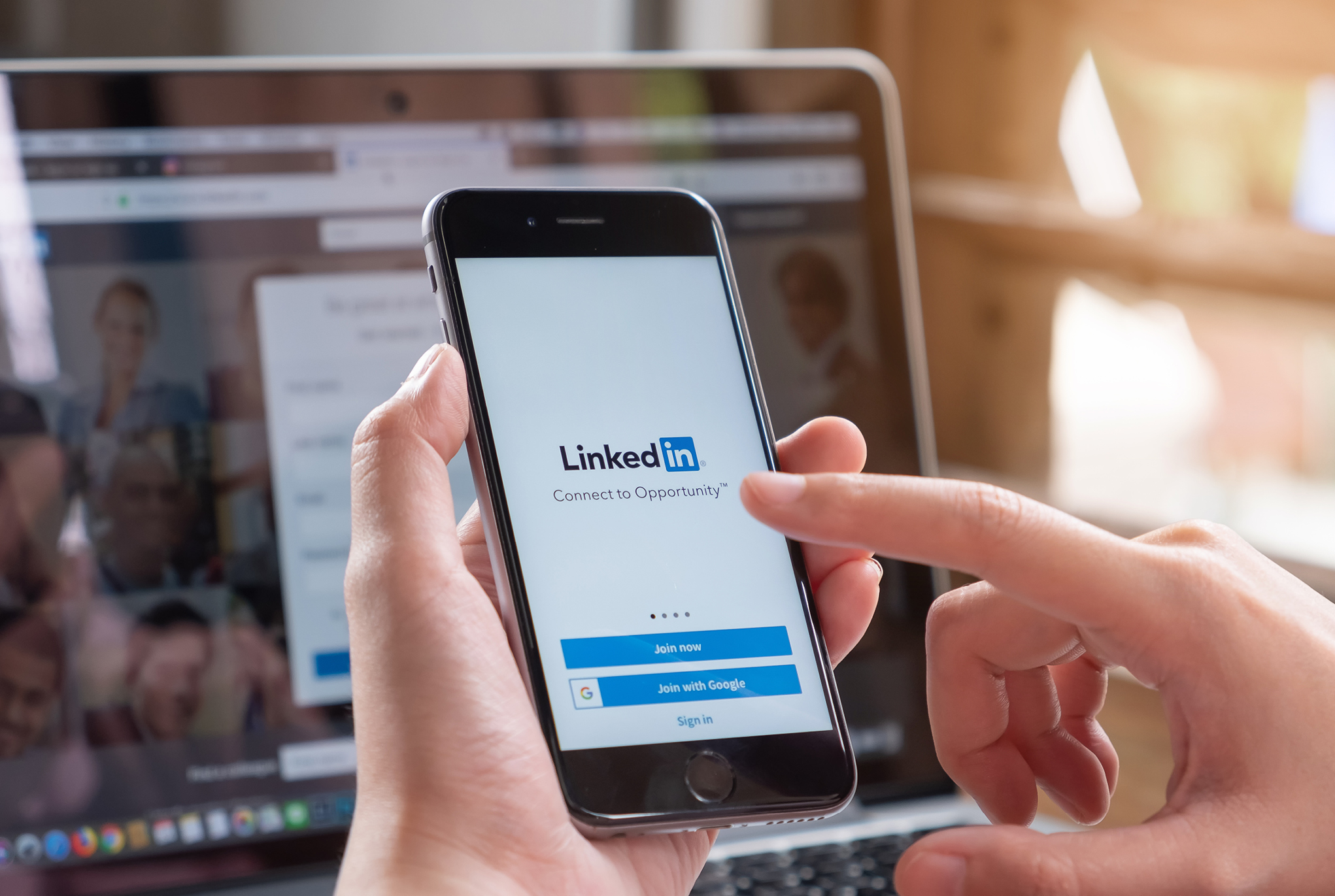 A person holding their phone logging in to LinkedIn