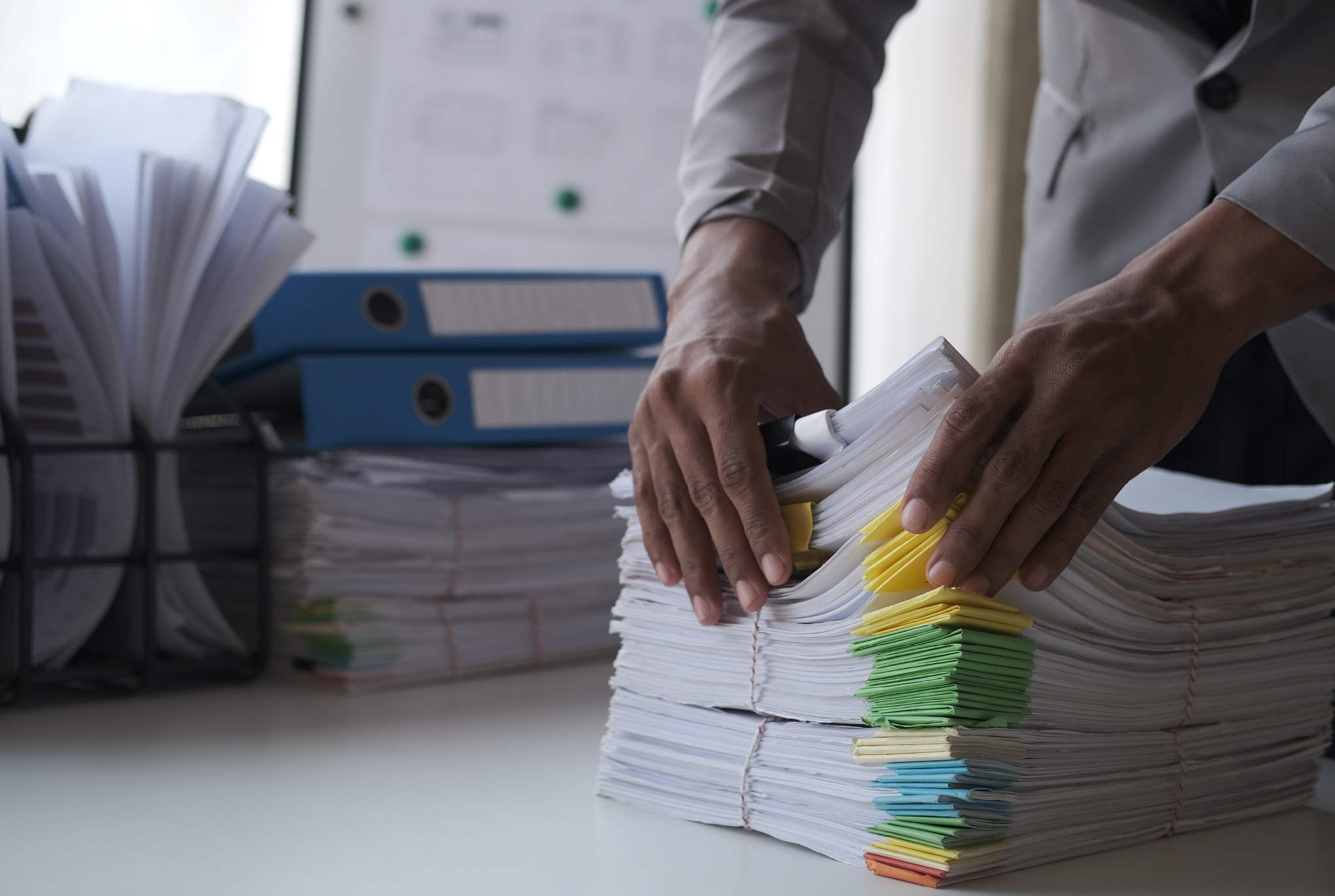 A person holding a stack of papers on a desk