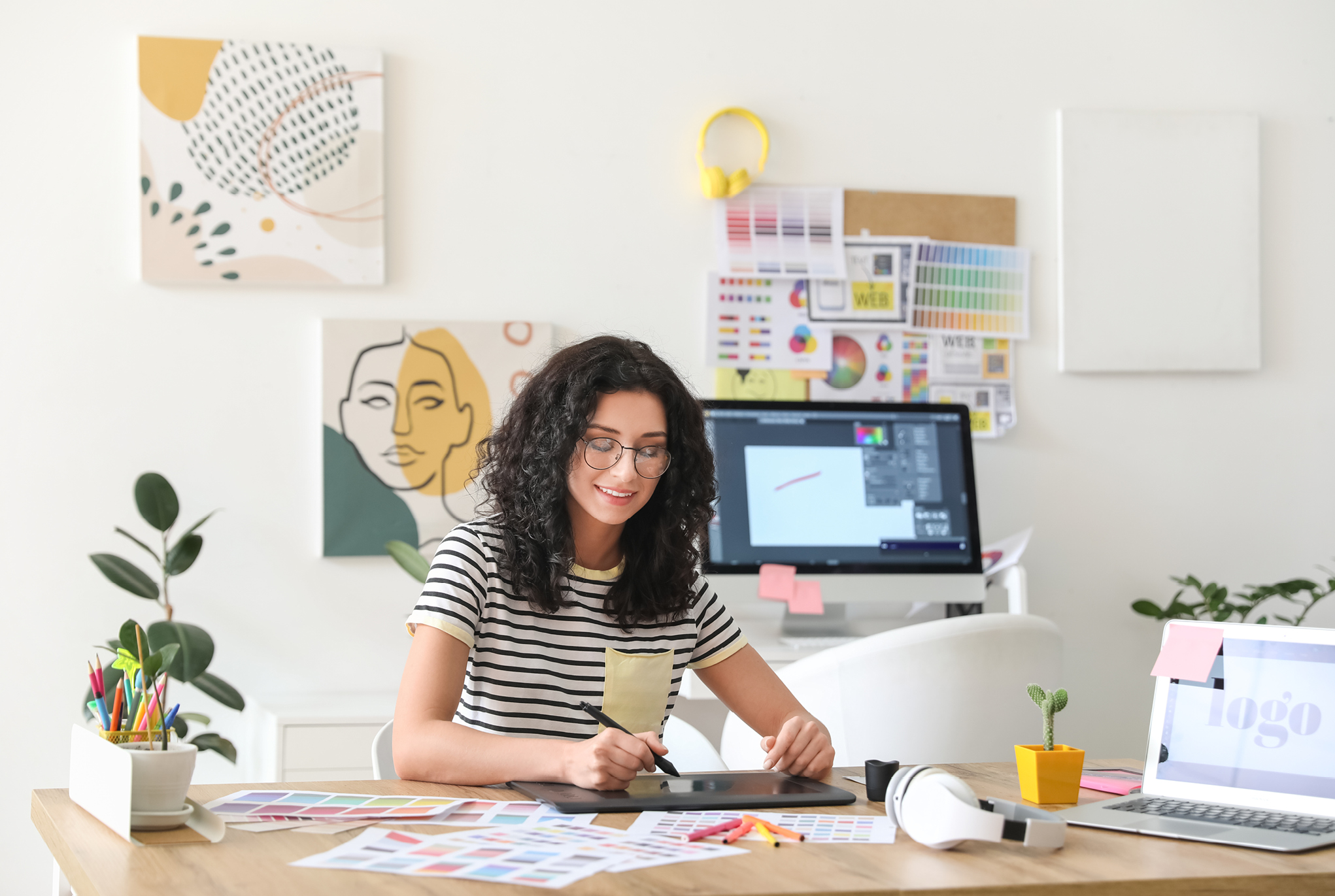 A woman sitting at a desk working on a tablet