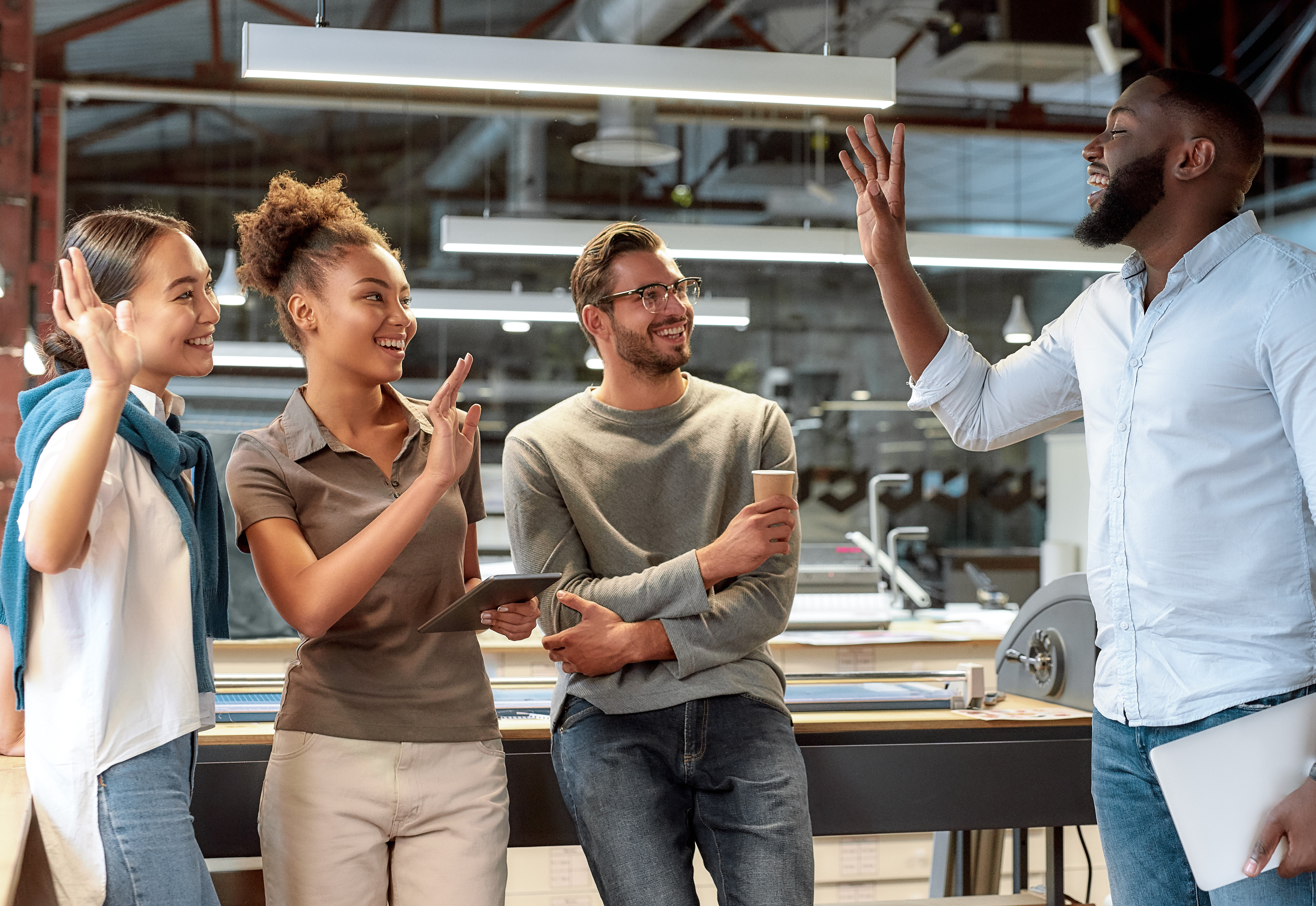 A group of four people in an office waving to each other. 