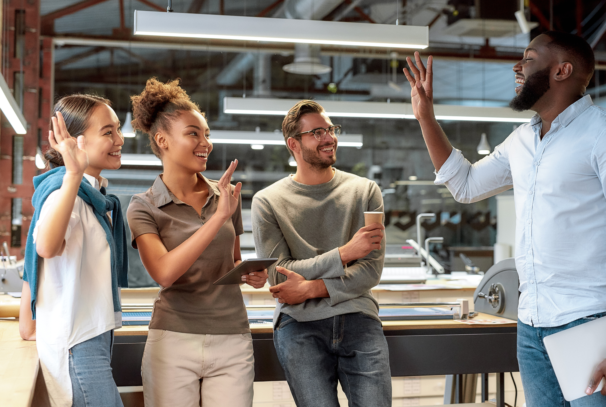 A group of four people in an office waving to each other.