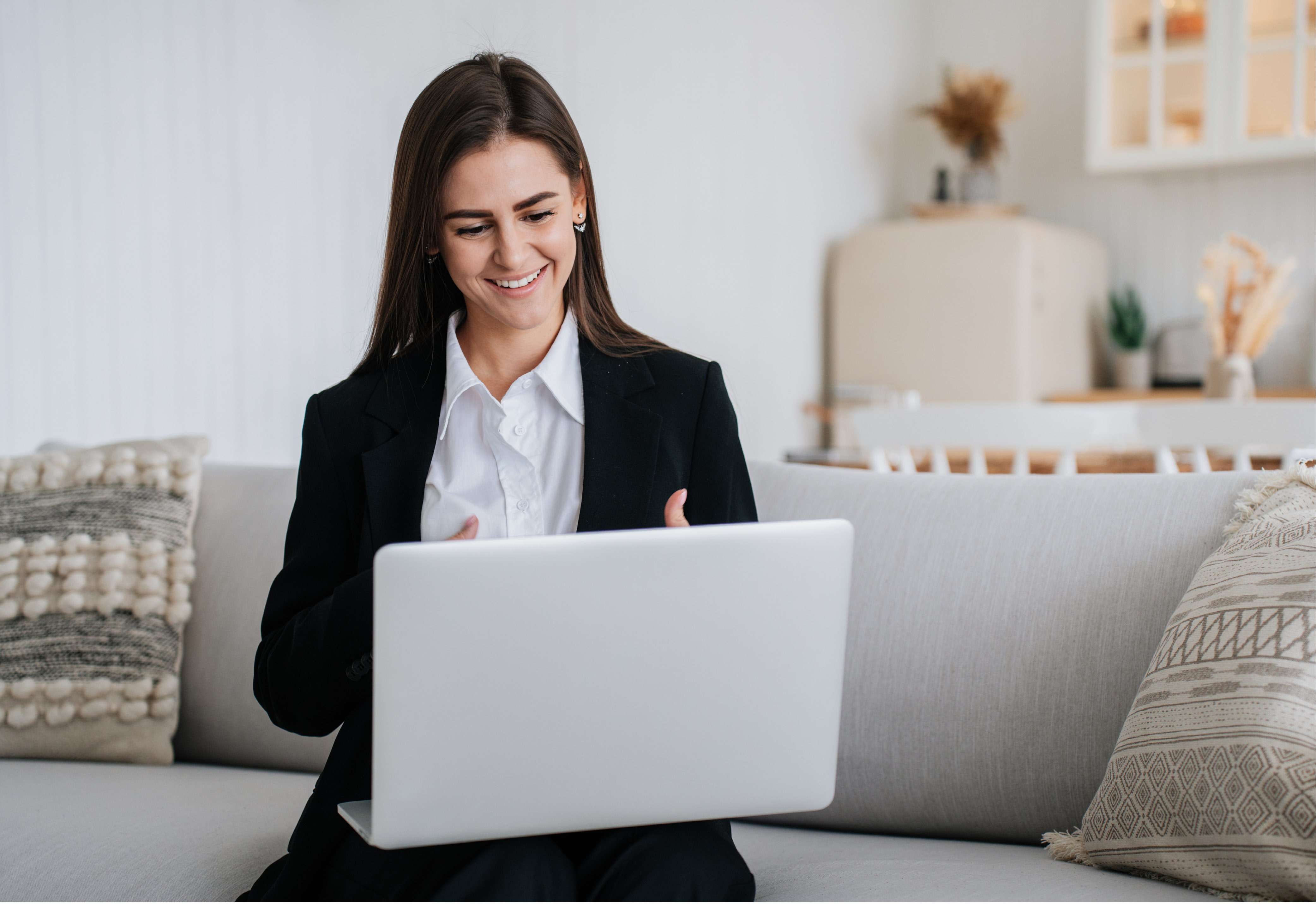 A woman sitting on a sofa having a virtual meeting on her laptop