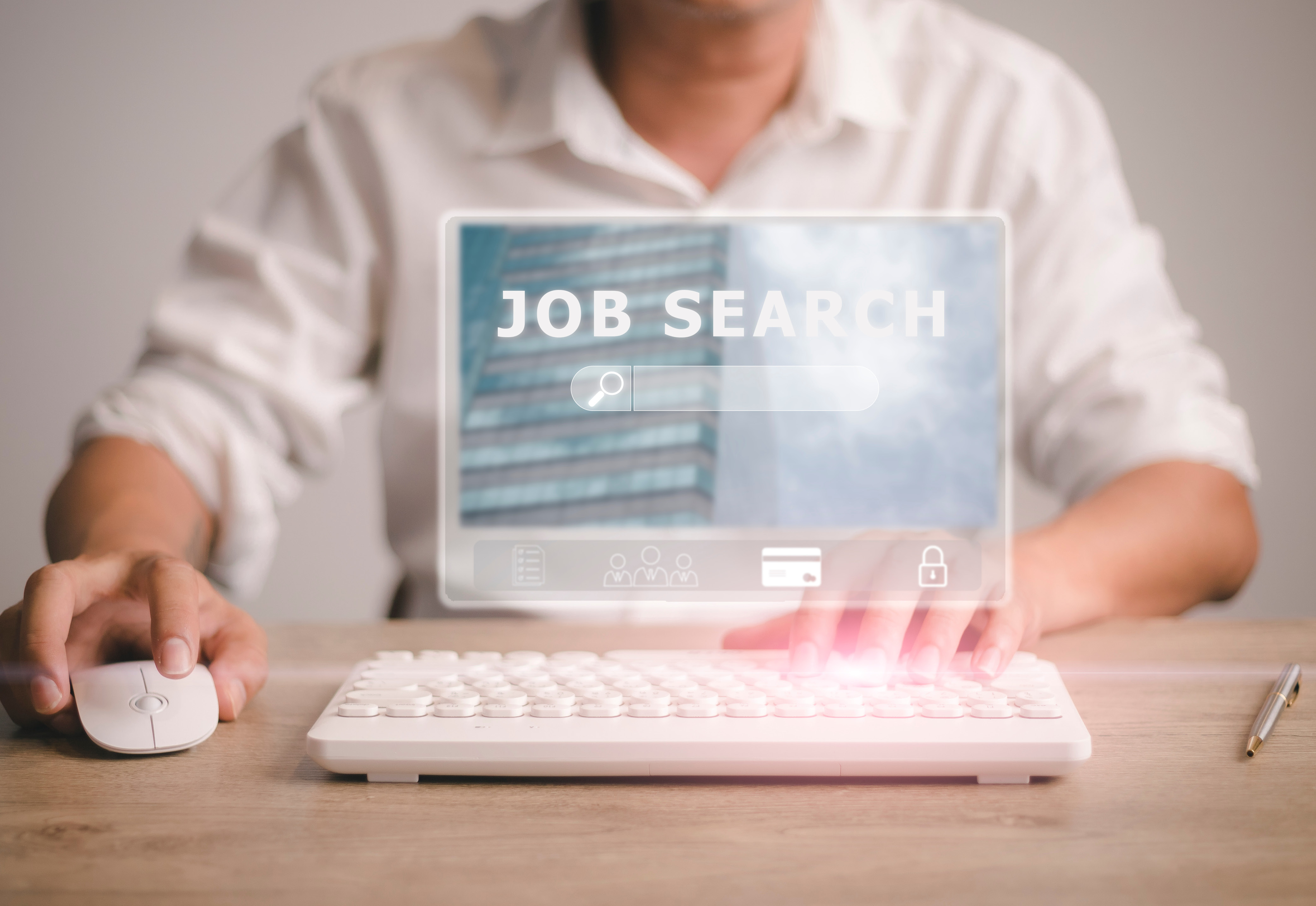 A person sitting at a desk using a keyboard and mouse to look for a job