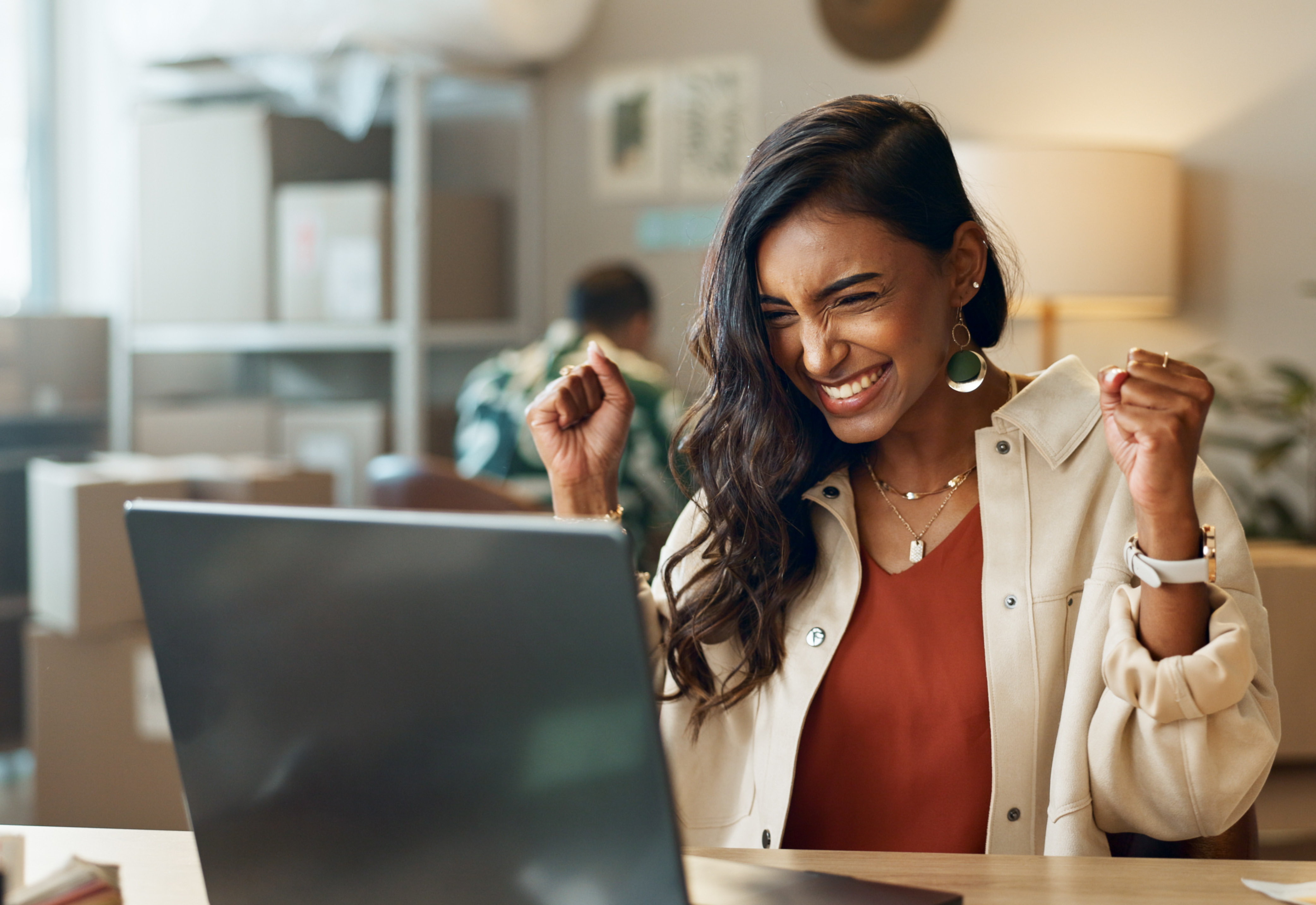 A woman sitting at a desk in front of a laptop smiling