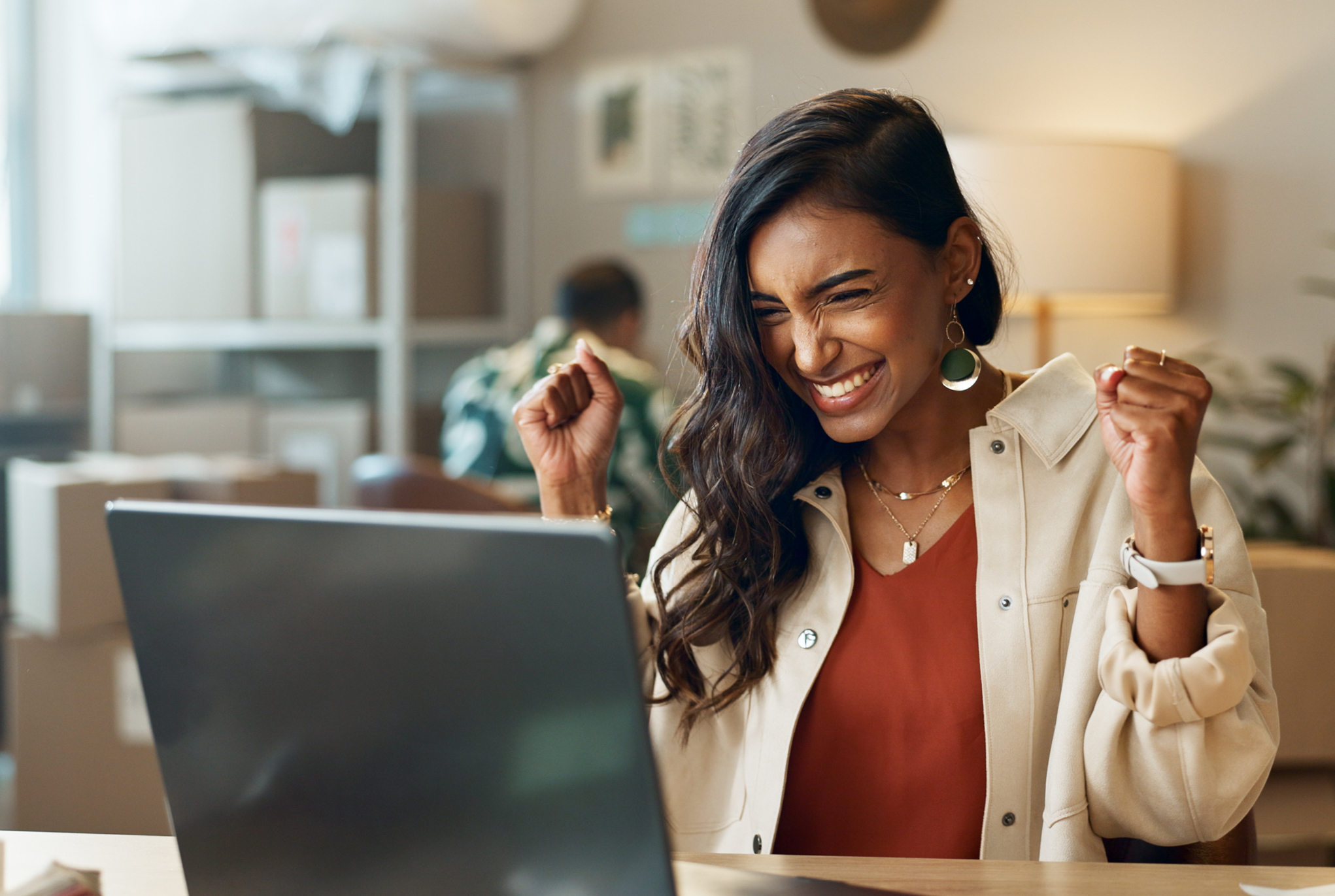 A woman sitting at a desk in front of a laptop smiling