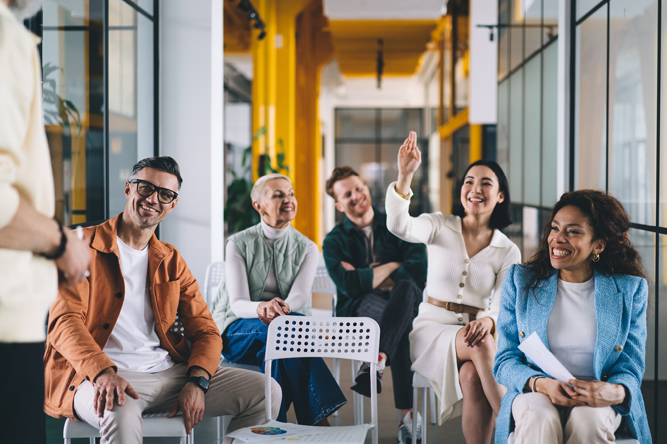 A group of people sitting together with one person raising their hand