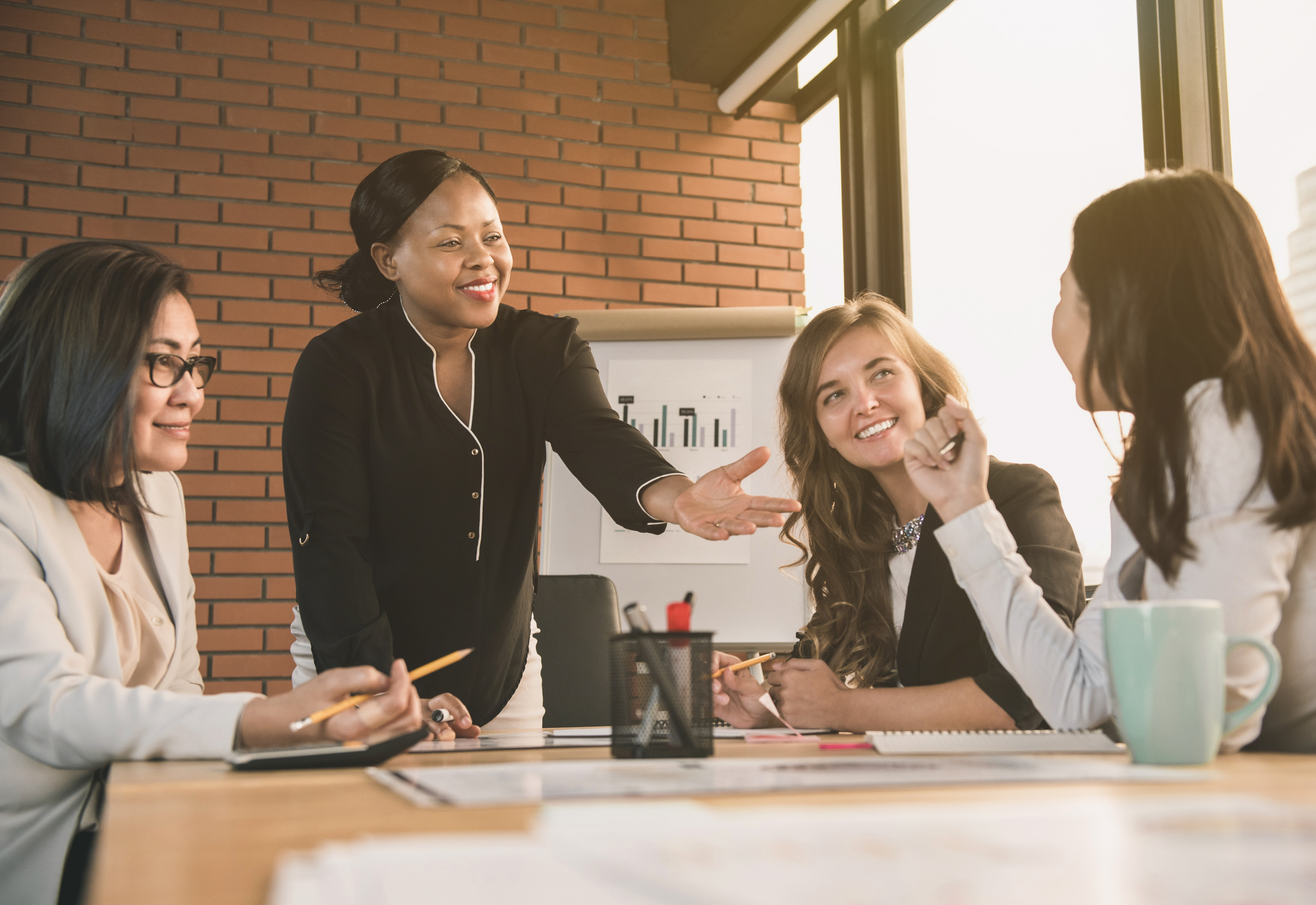 A group of women gathered around a table smiling at each other