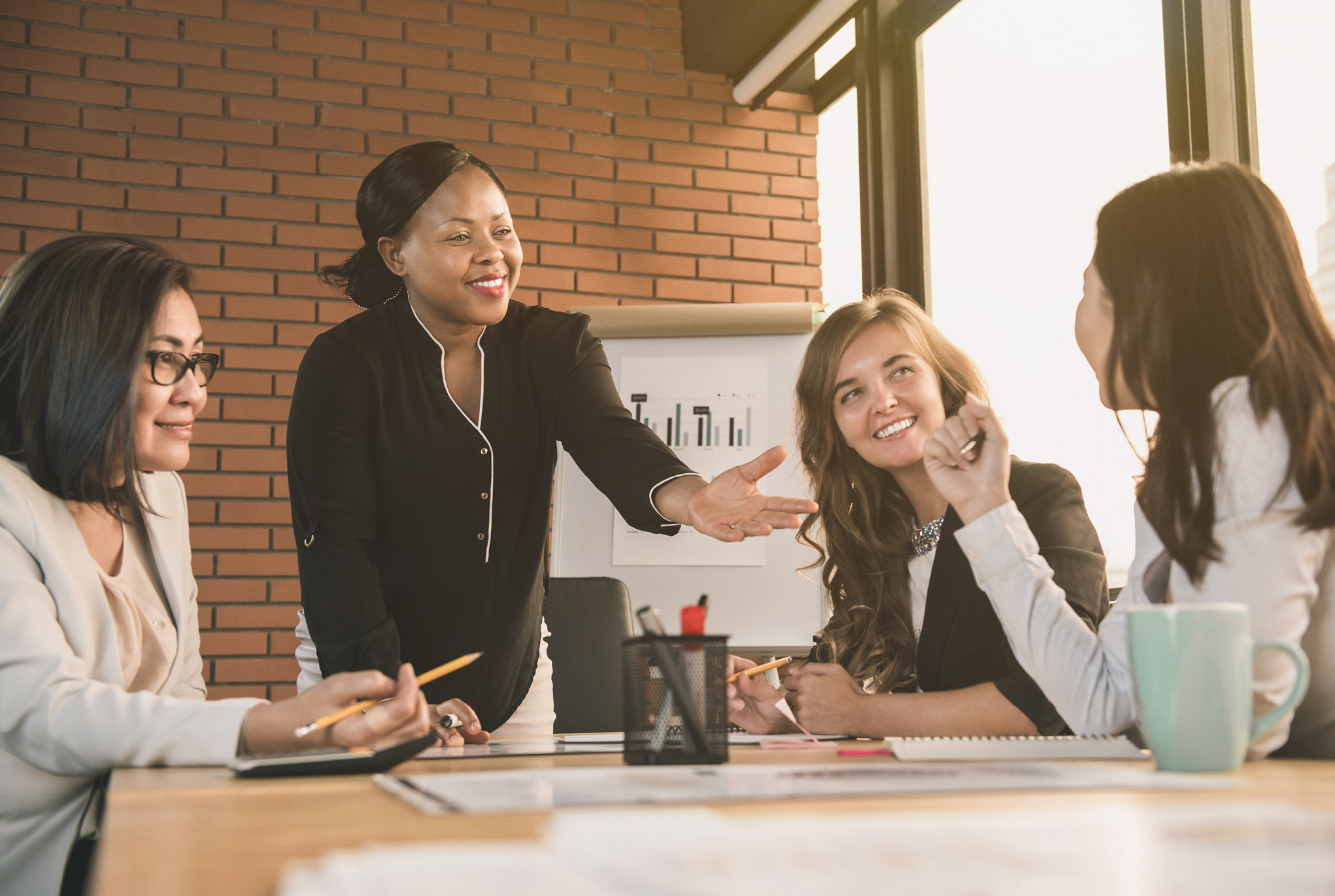 A group of women gathered around a table smiling at each other