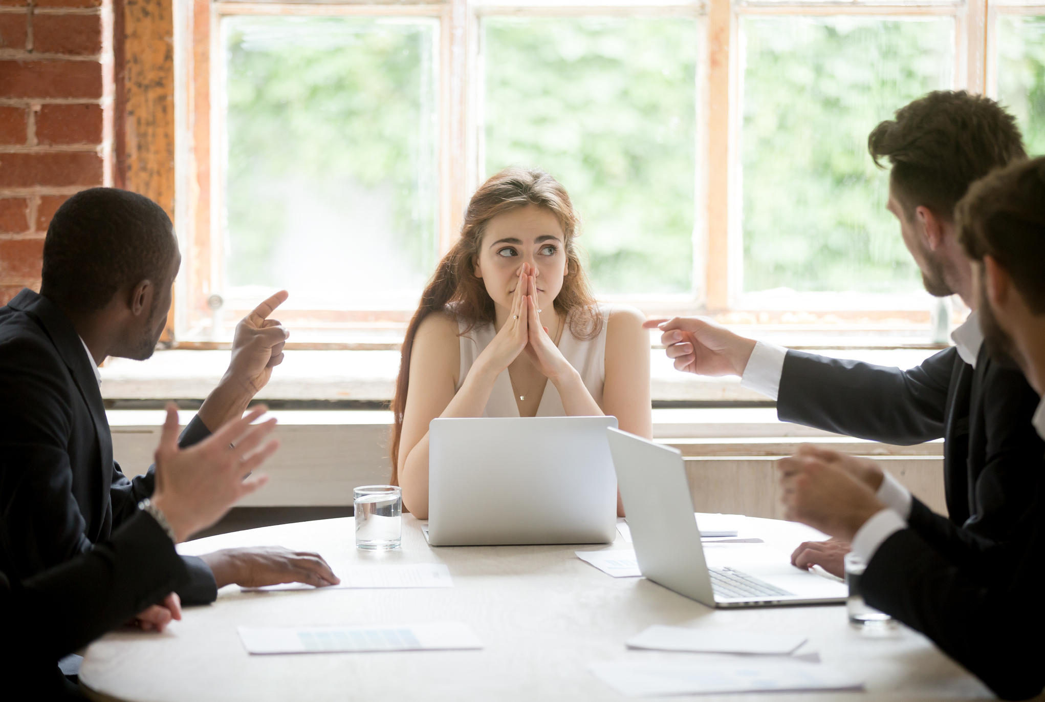 A group of people sitting at a table and pointing fingers at someone