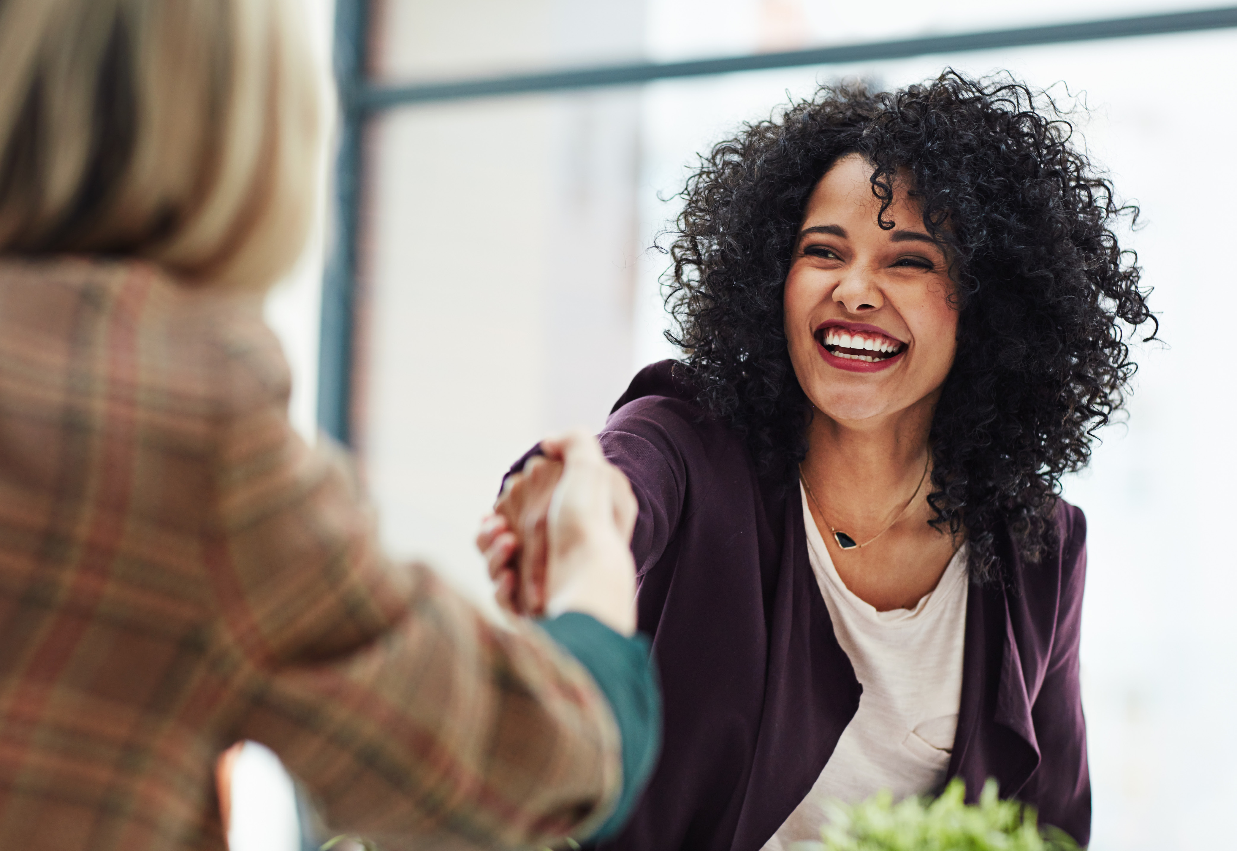 Two women shaking hands and smiling 