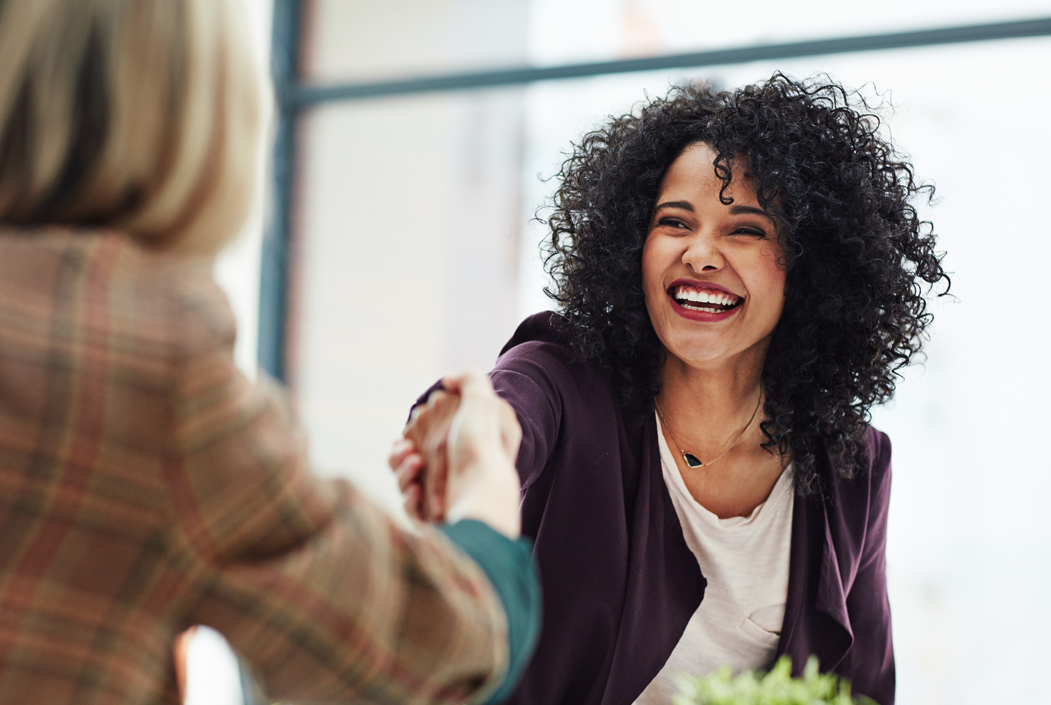 Two women shaking hands and smiling 