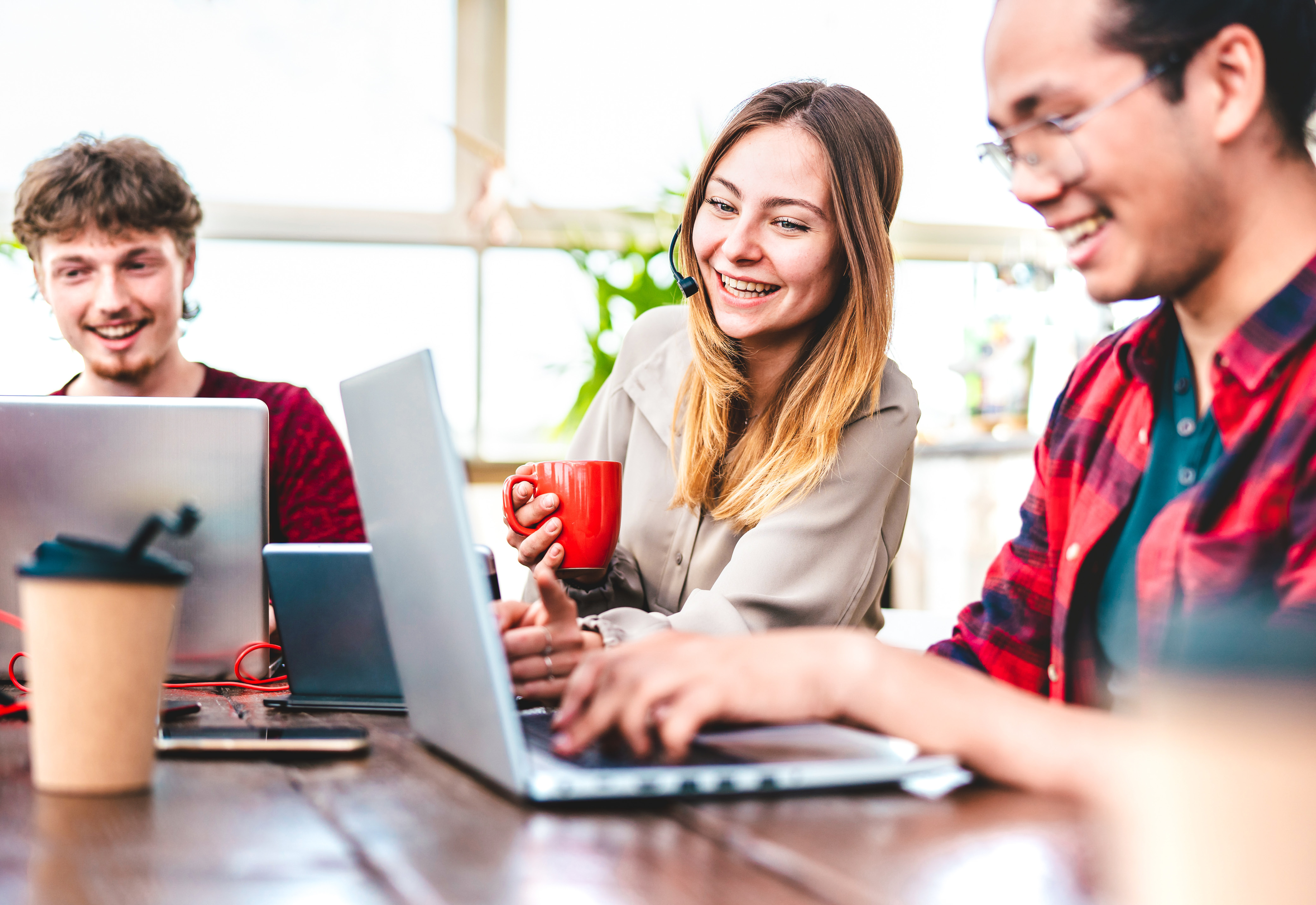 A group of people sitting around a table with laptops and cups of coffee