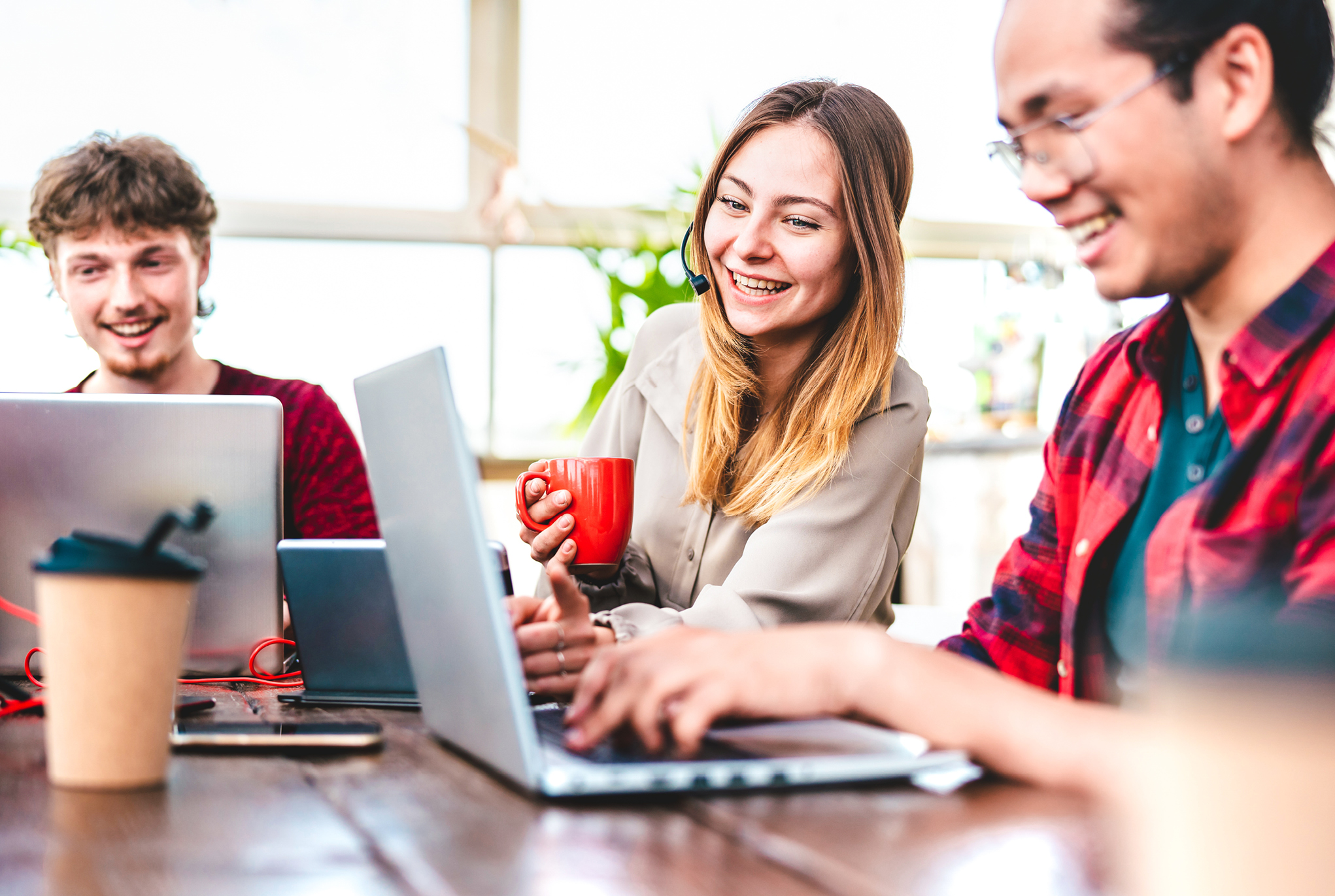 A group of people sitting around a table with laptops and cups of coffee