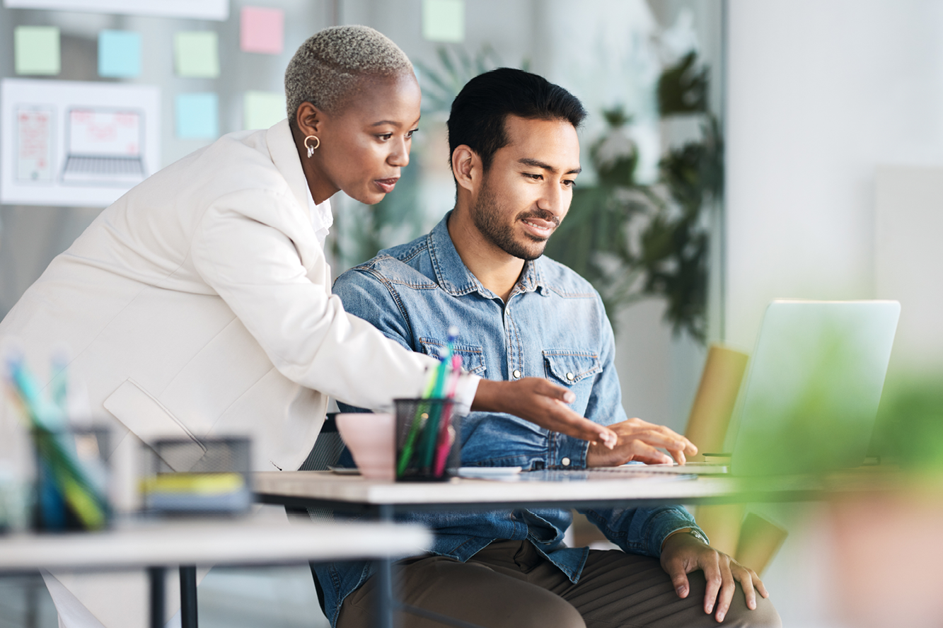 A woman helping a man with something on his laptop