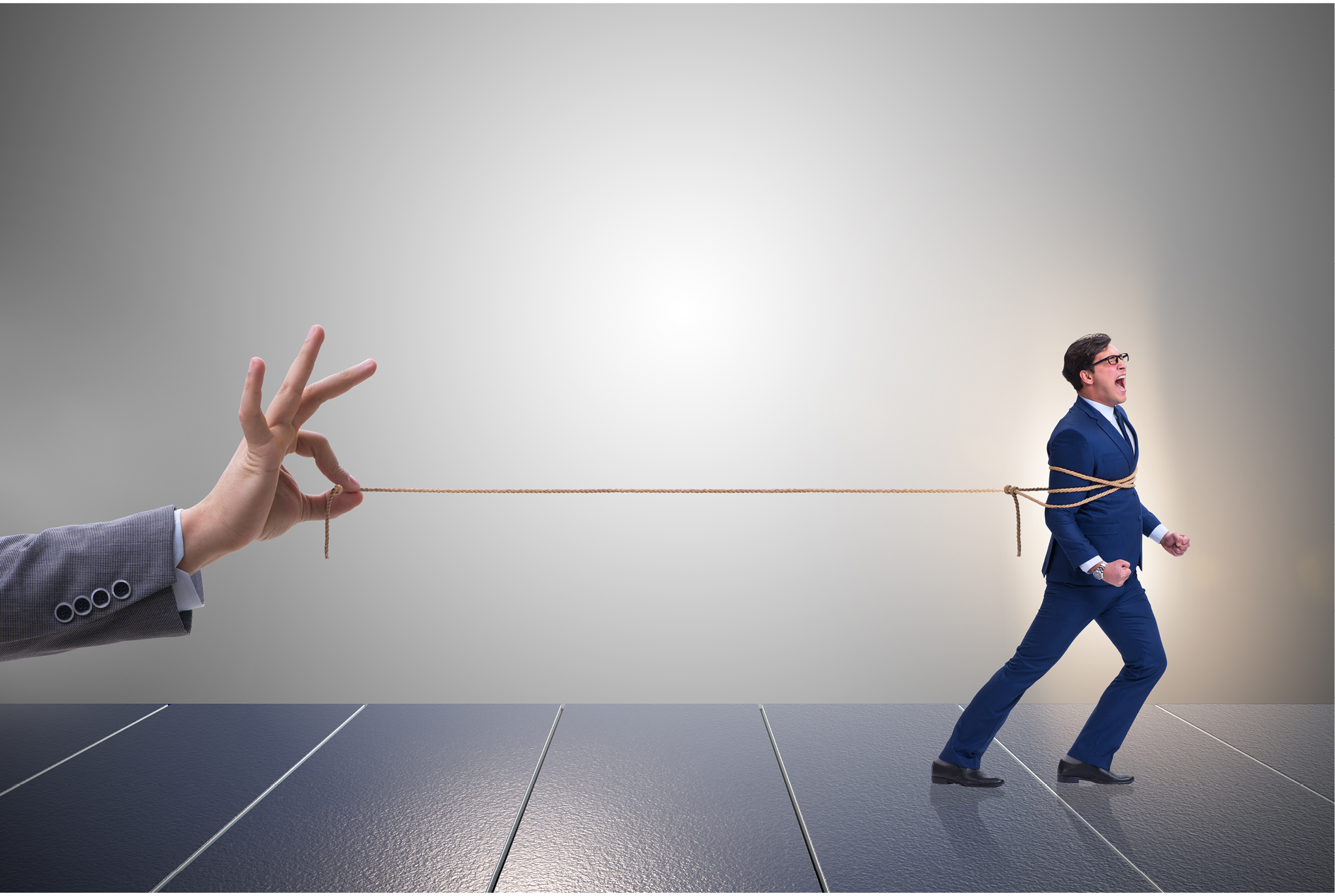 A person's hand holding a rope tied around a man in business attire