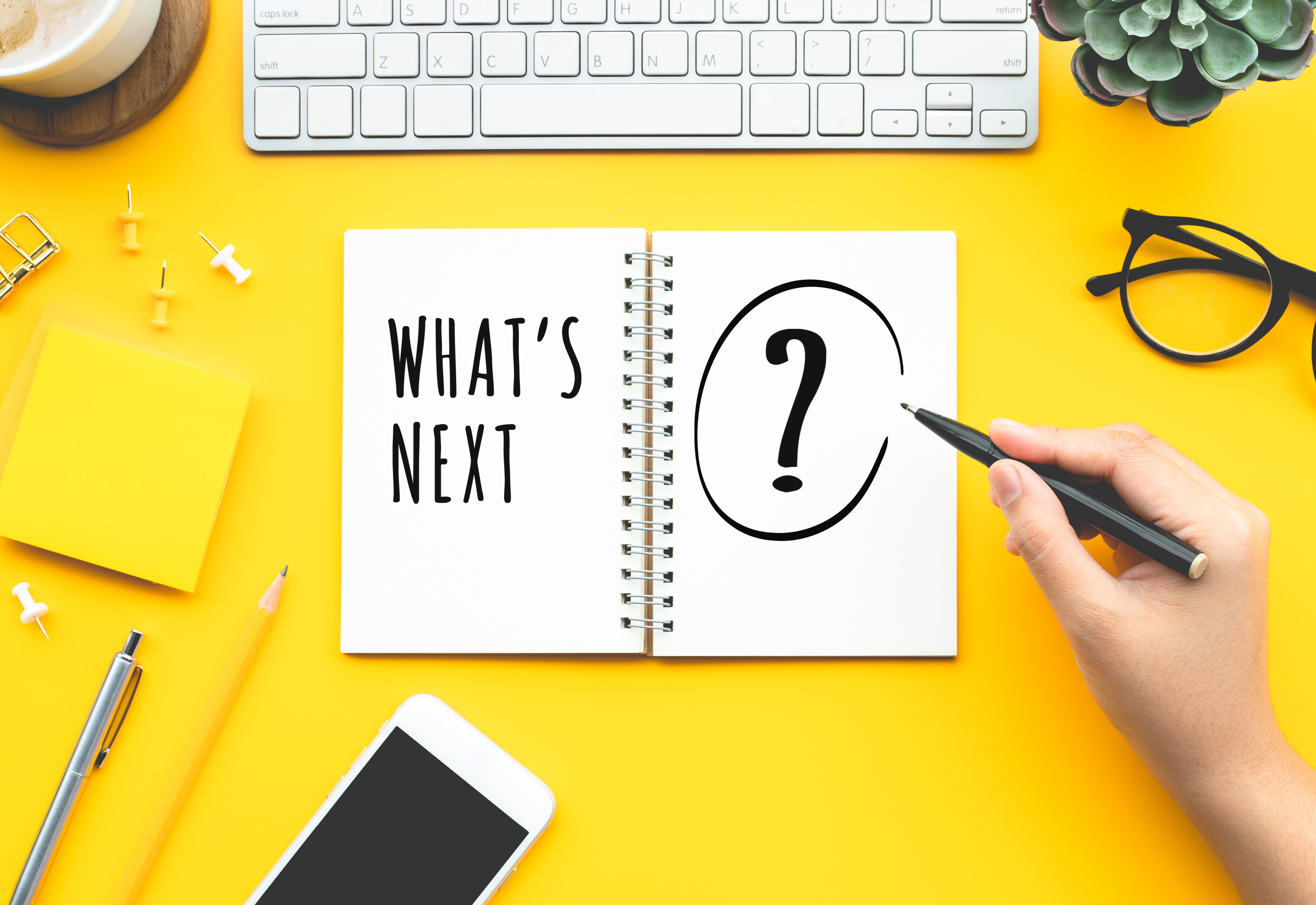 An open notebook on a desk that says, "What's Next?" on the pages