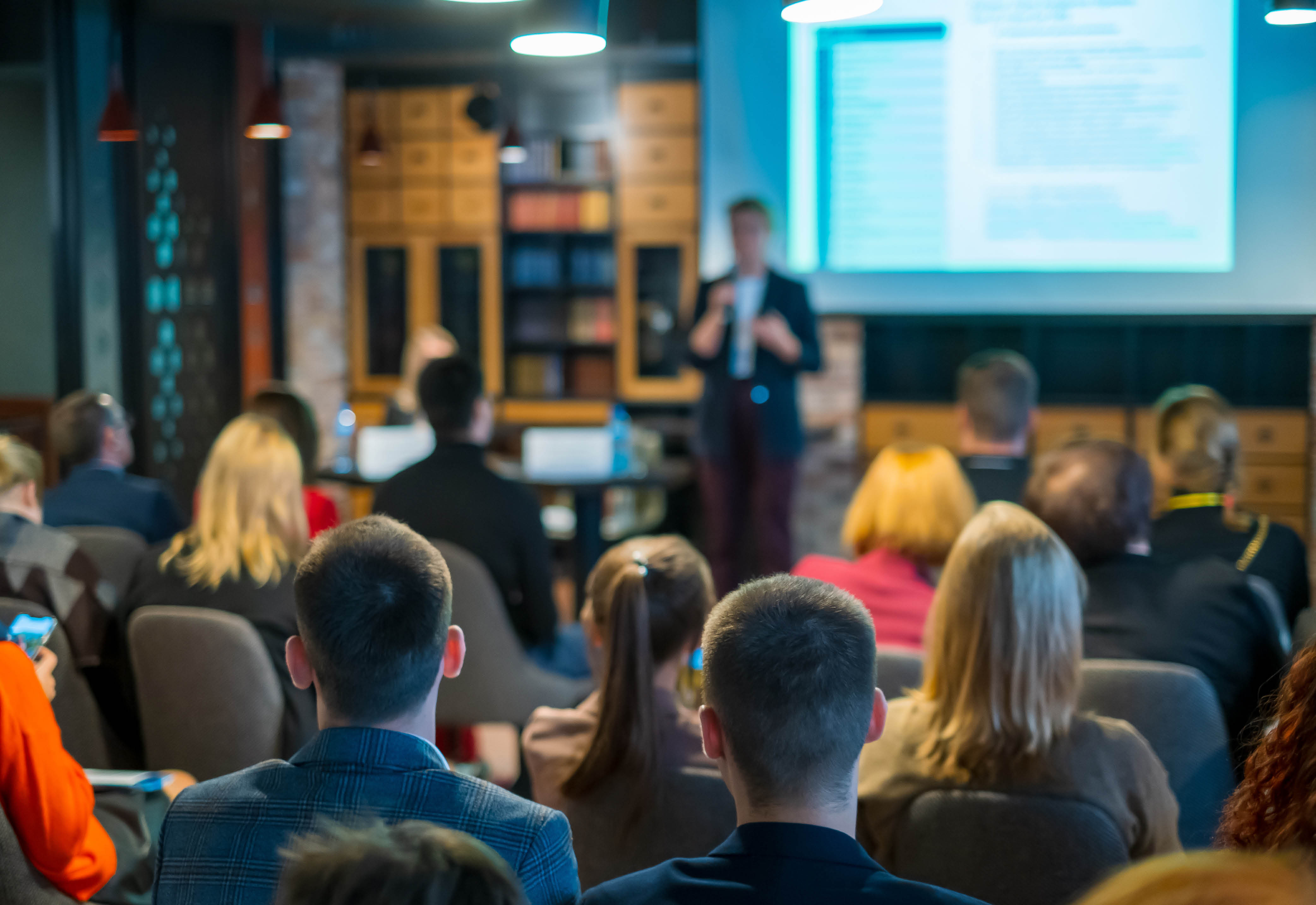 A group of people sitting in an audience watching a presentation