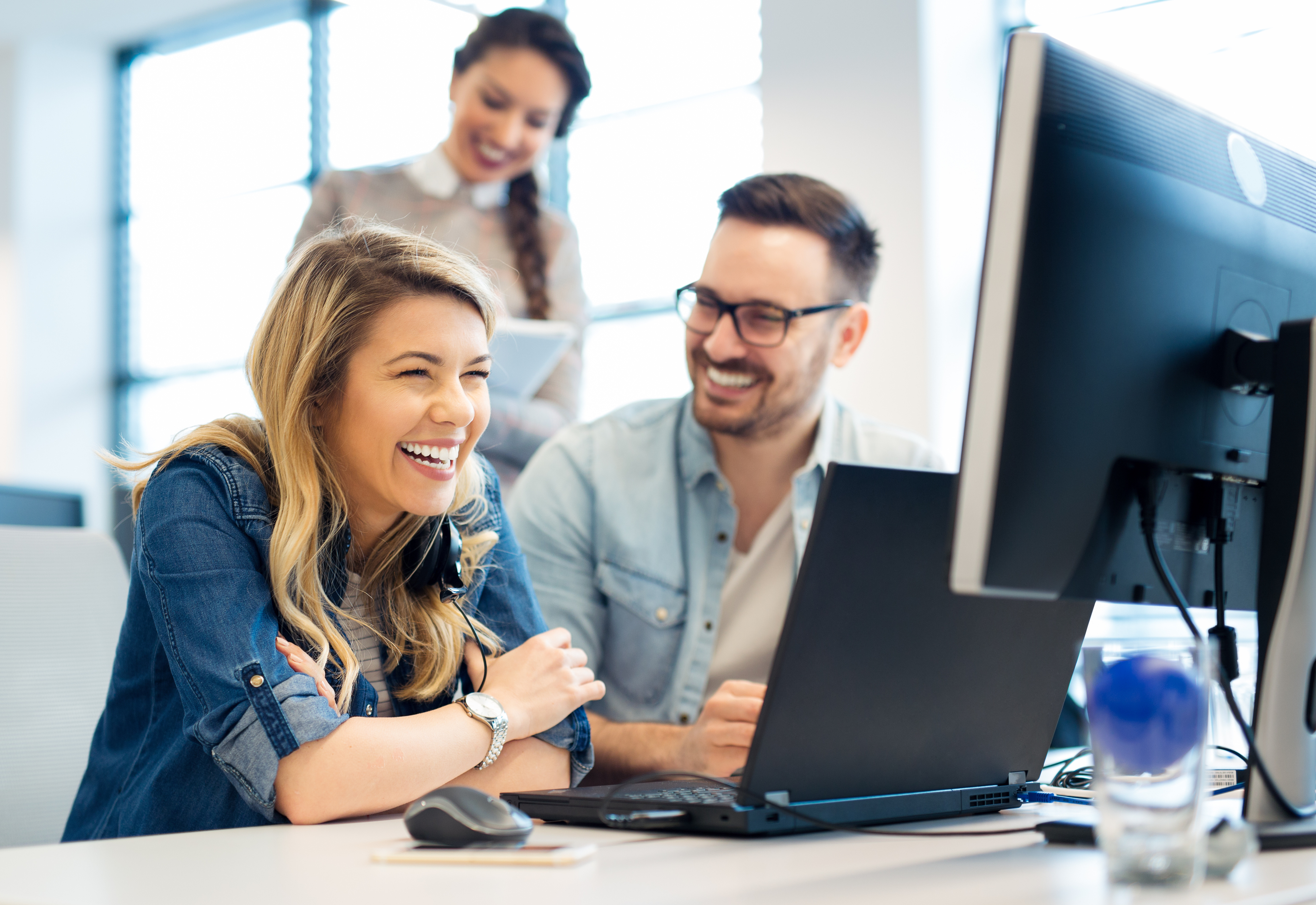 A group of people sitting at a desk with a computer