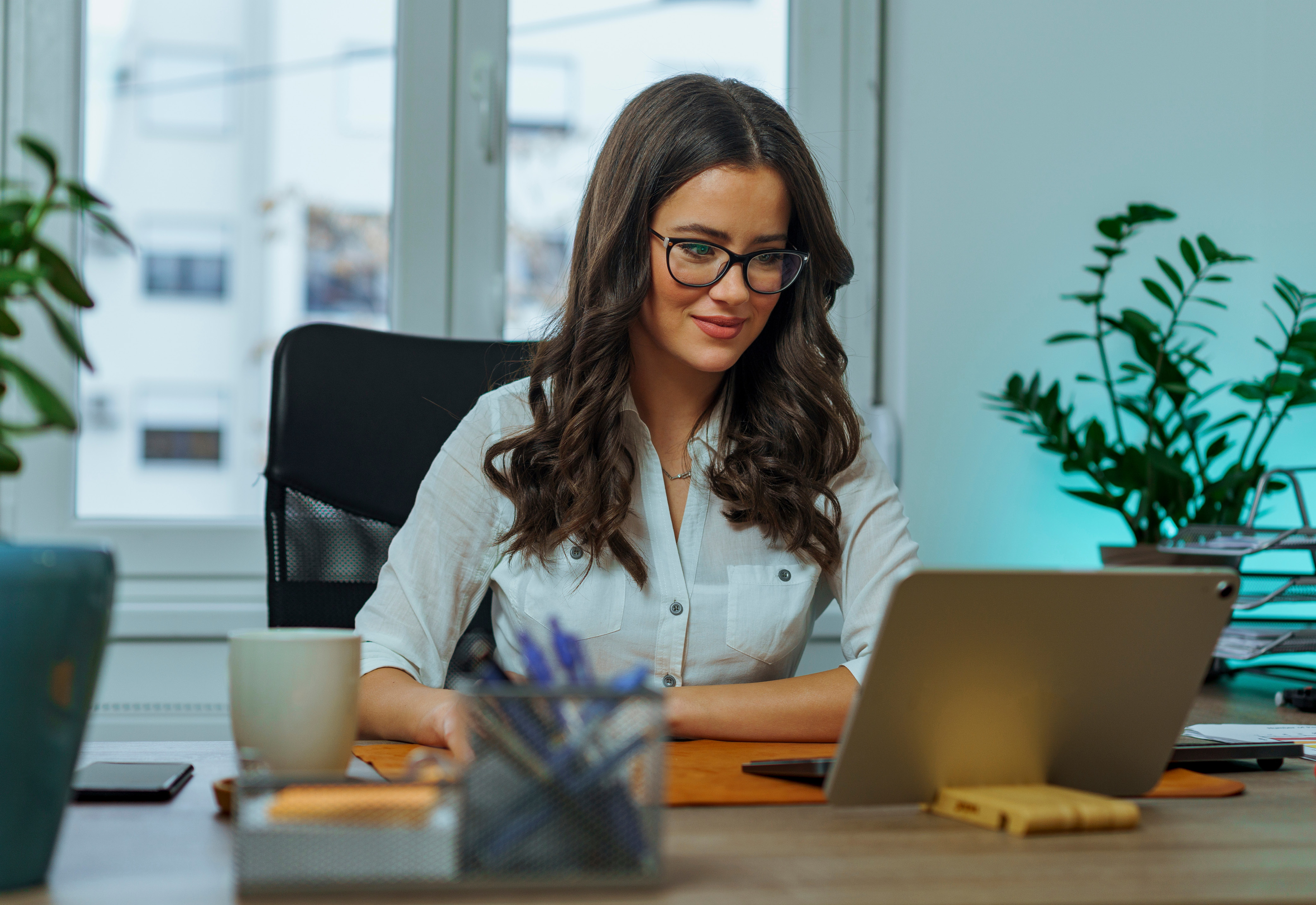 A woman sitting at her desk wearing glasses