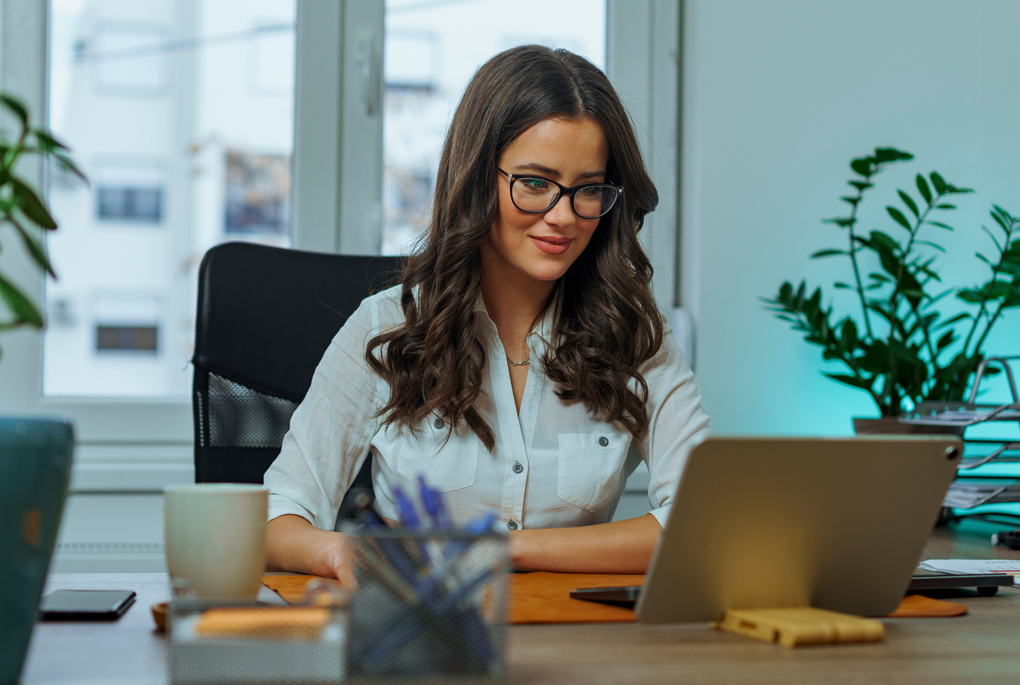 A woman sitting at her desk wearing glasses