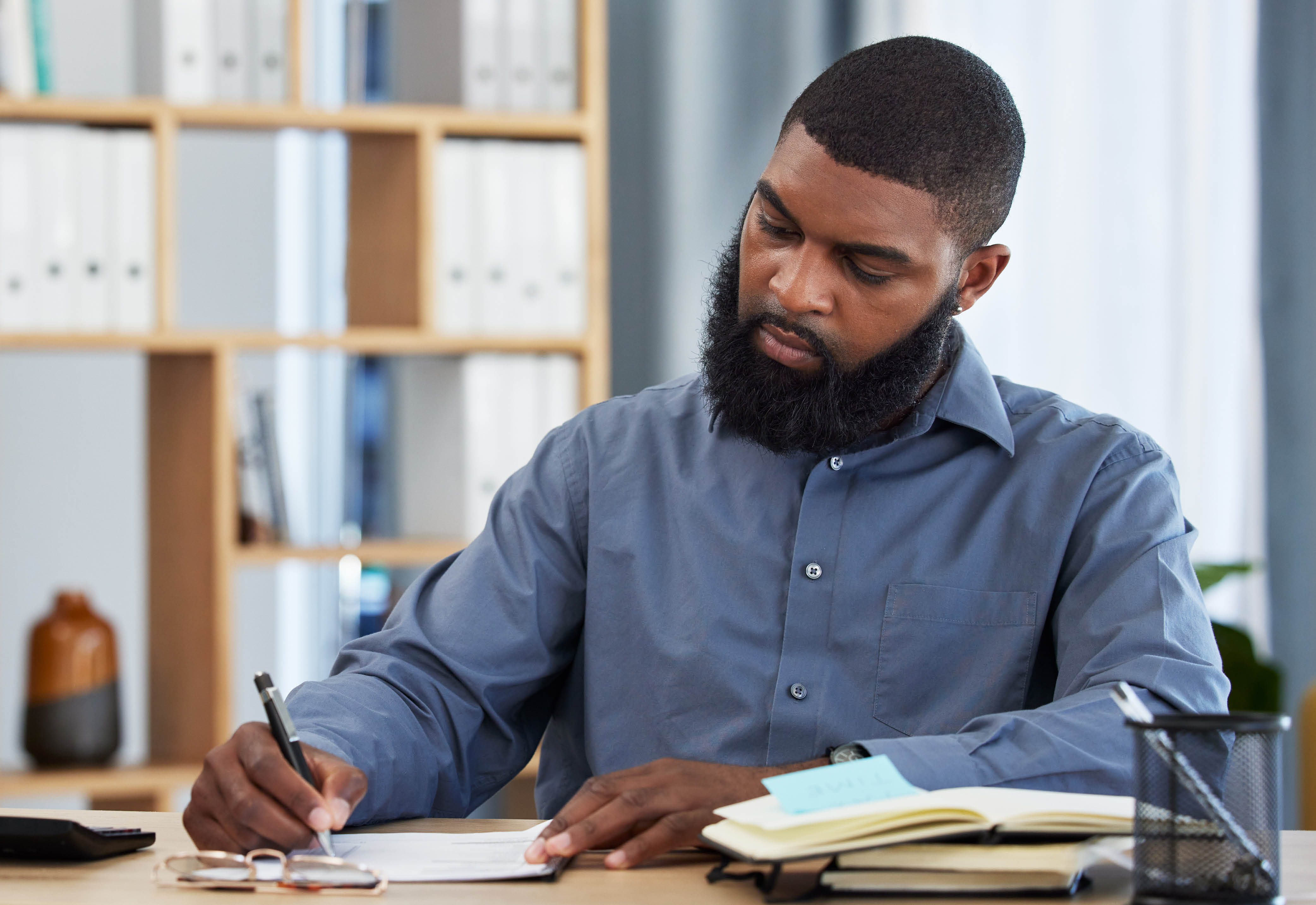 Man sitting at a desk writing in a notebook. 