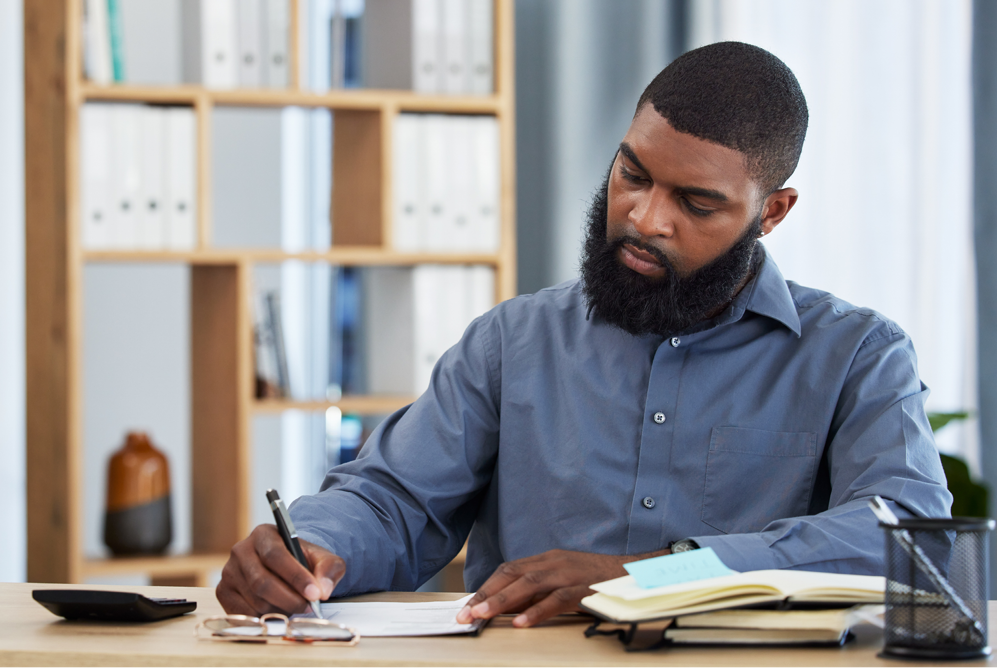 Man sitting at a desk writing in a notebook. 