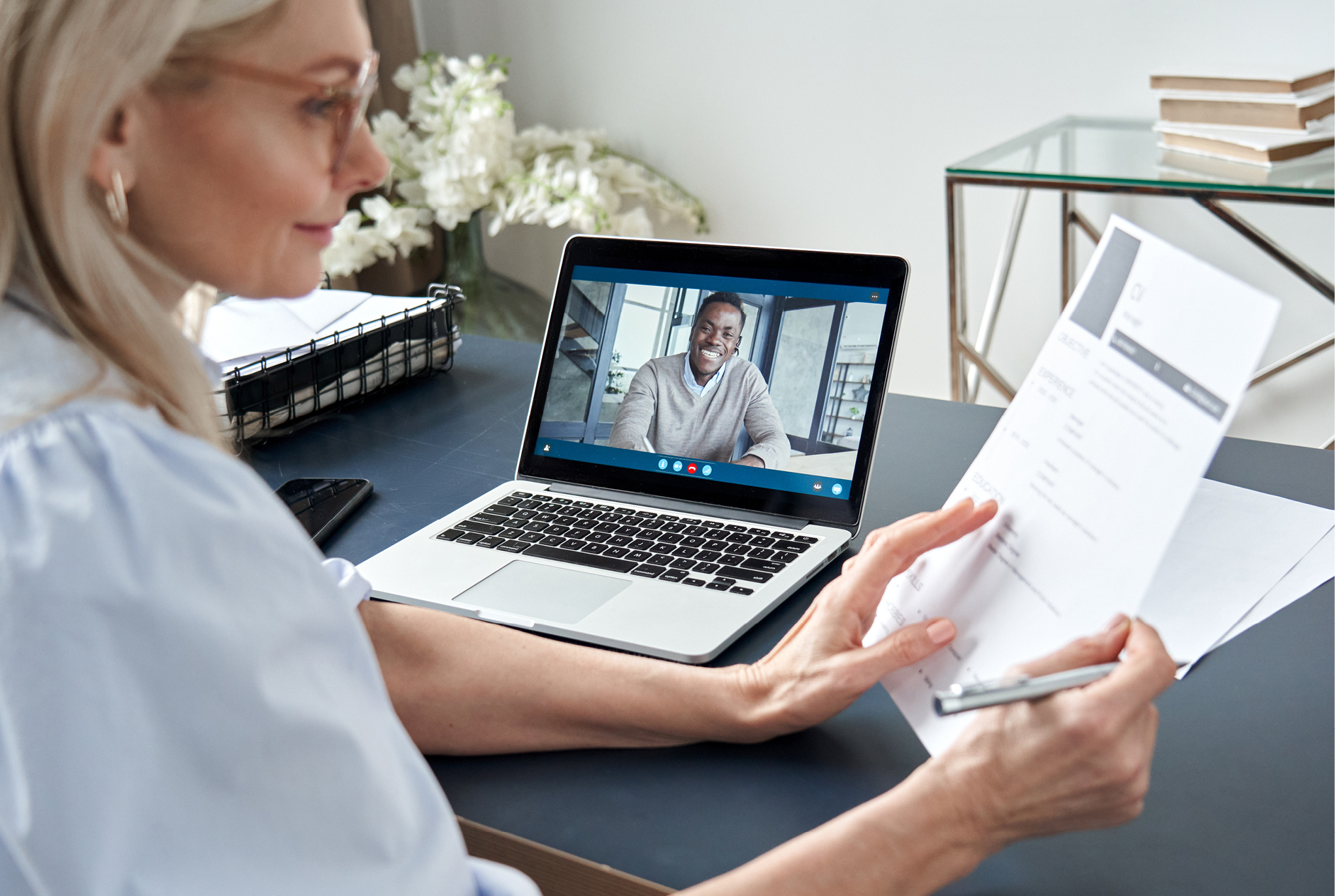 A woman conducting a virtual job interview with a candidate.