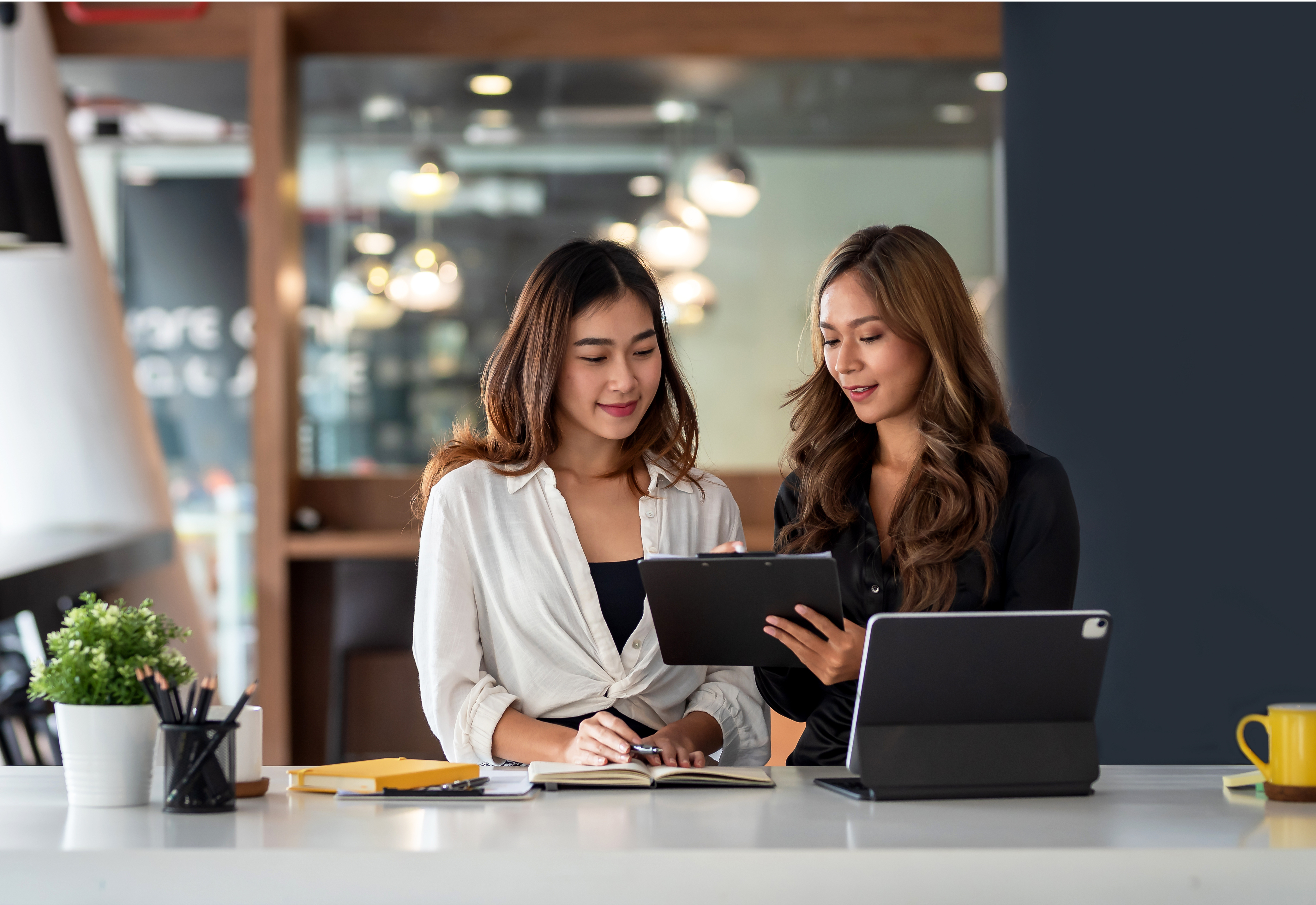 Two women in an office looking at a tablet together