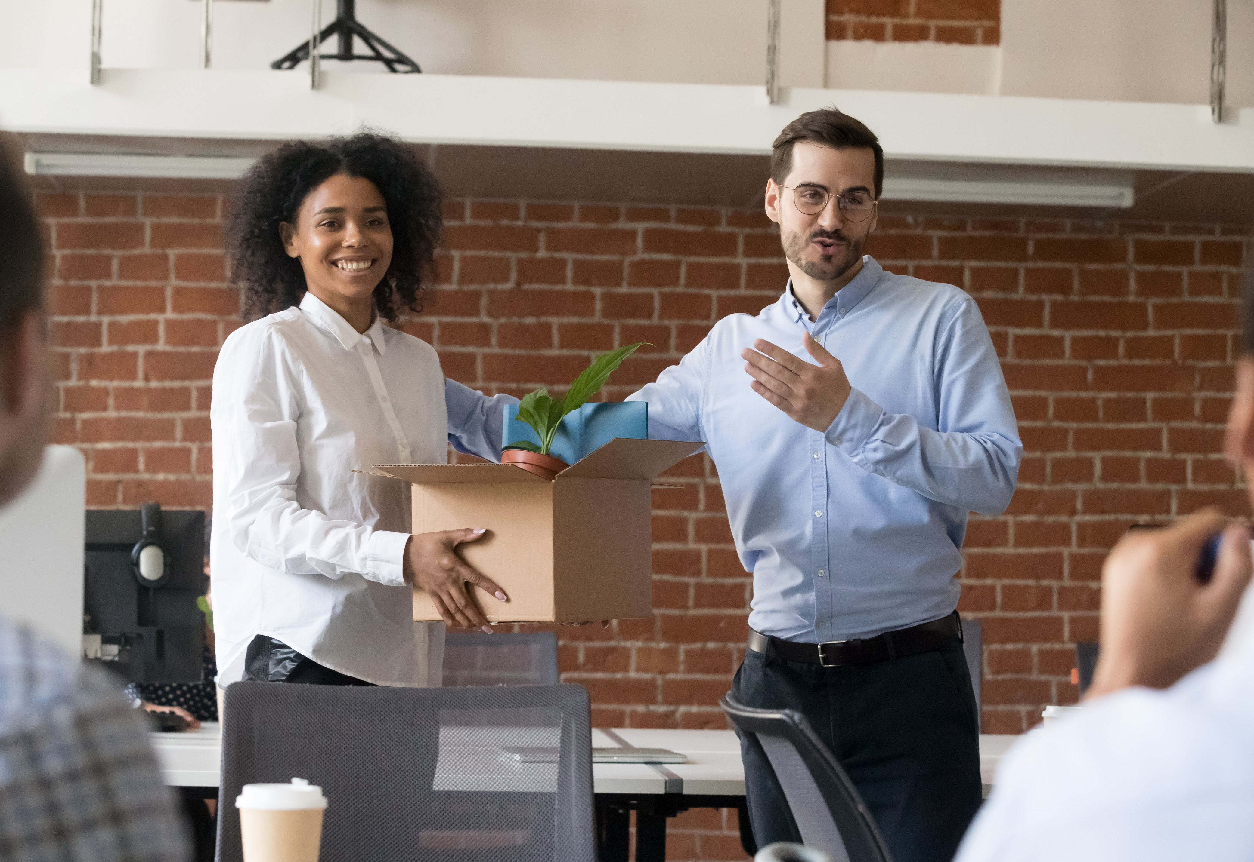 A new employee holding a box of belongings being introduced in the office