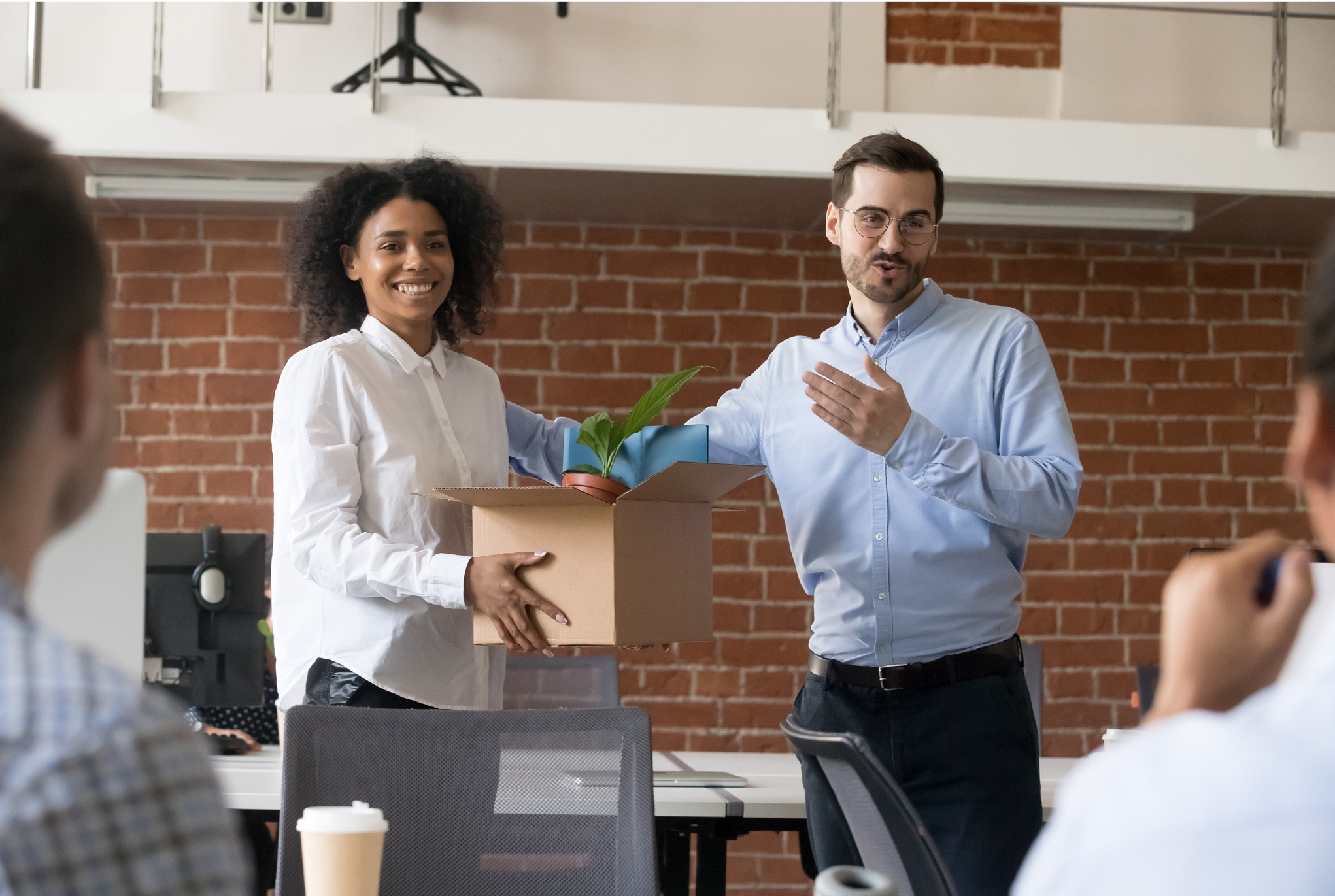 A new employee holding a box of belongings being introduced in the office